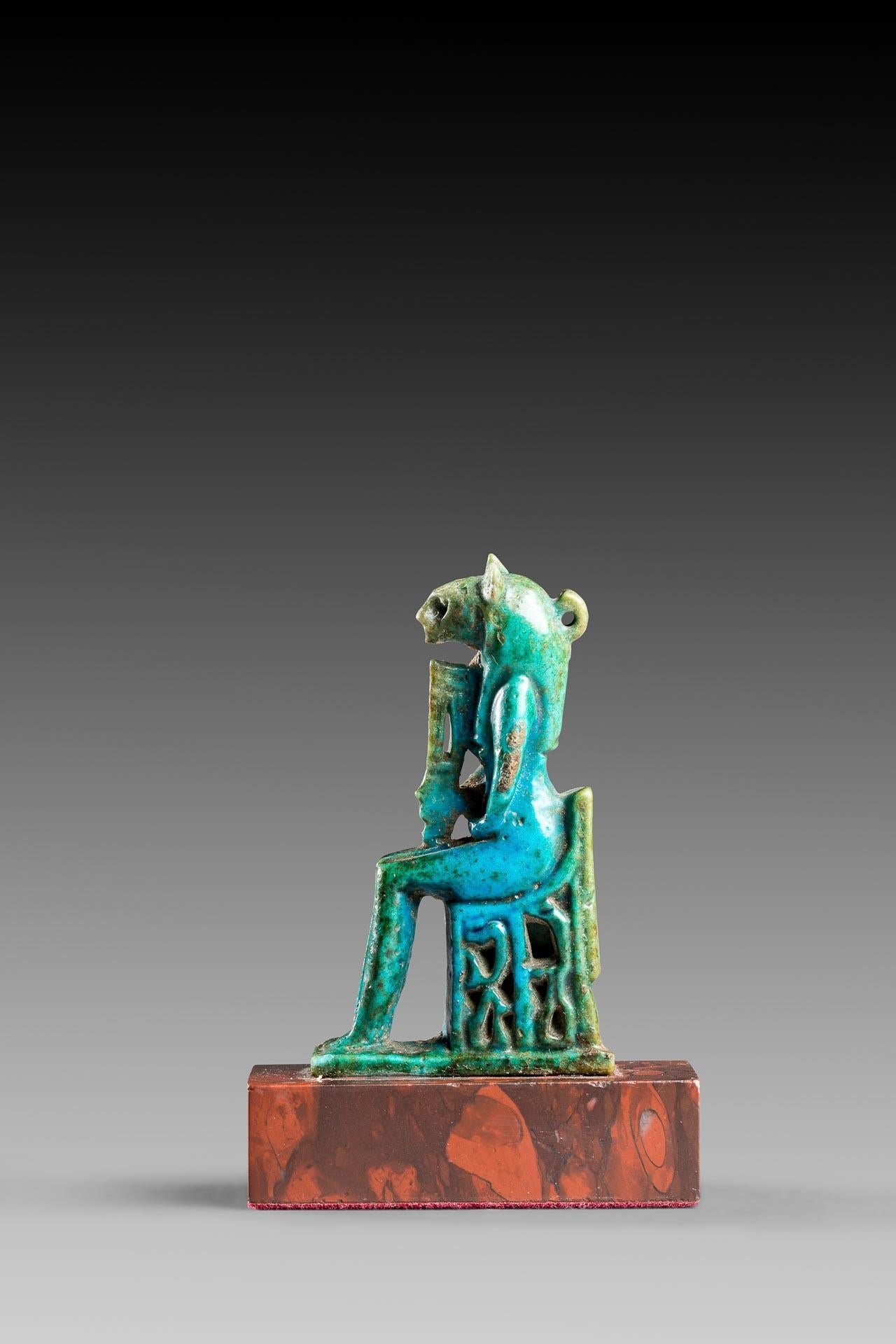 Turquoise blue faience

Amulet representing the Egyptian goddess Sekhmet sitting on a throne, which is decorated with two Nehebkau and engraved on the back with the Ankh symbol. She holds a Hathor sistrum in her right hand. A solar disc used to