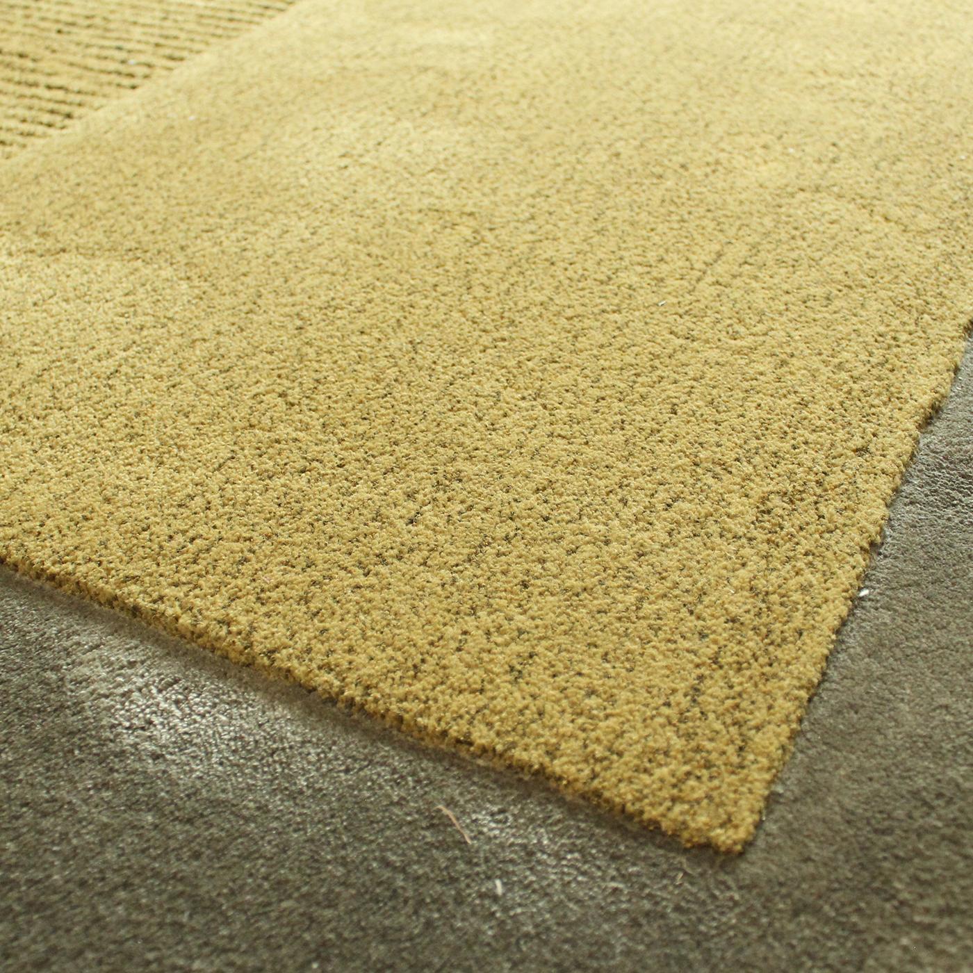 Warm greens, mustard yellow, and gray hues mix with bright yellow and red in this exquisite rug that combines an asymmetrical silhouette and a variety of textures obtained with the bouclè, velvet, relief, and shaggy techniques. The result is a