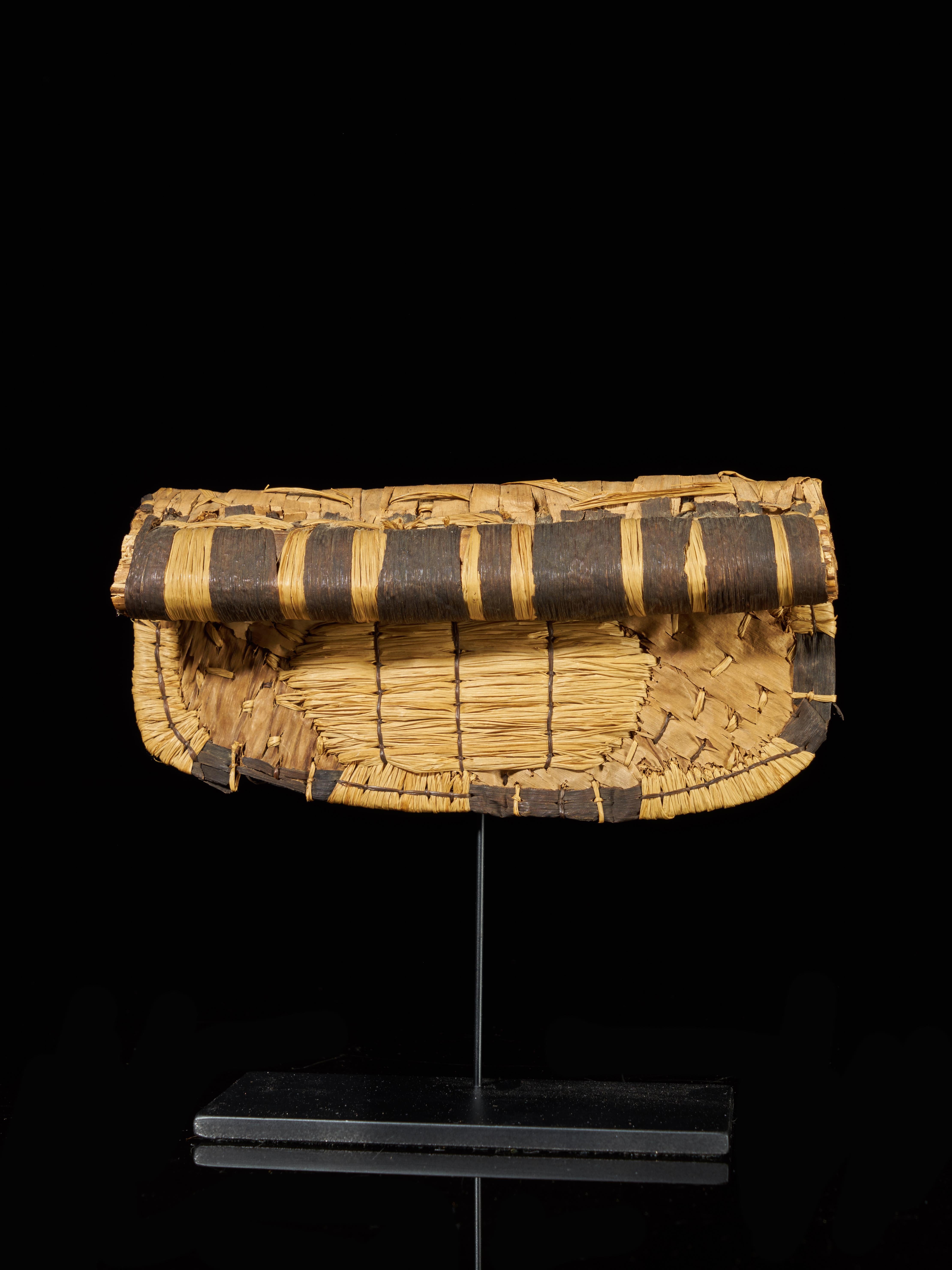 Back aprons (negbe, pl. egbe) such as these were particularly popular among upper-class Mangbetu women at the turn of the 20th century. This distinctive kidney-shaped ornament pad was built up of intricately layered banana leaves. Worn on special