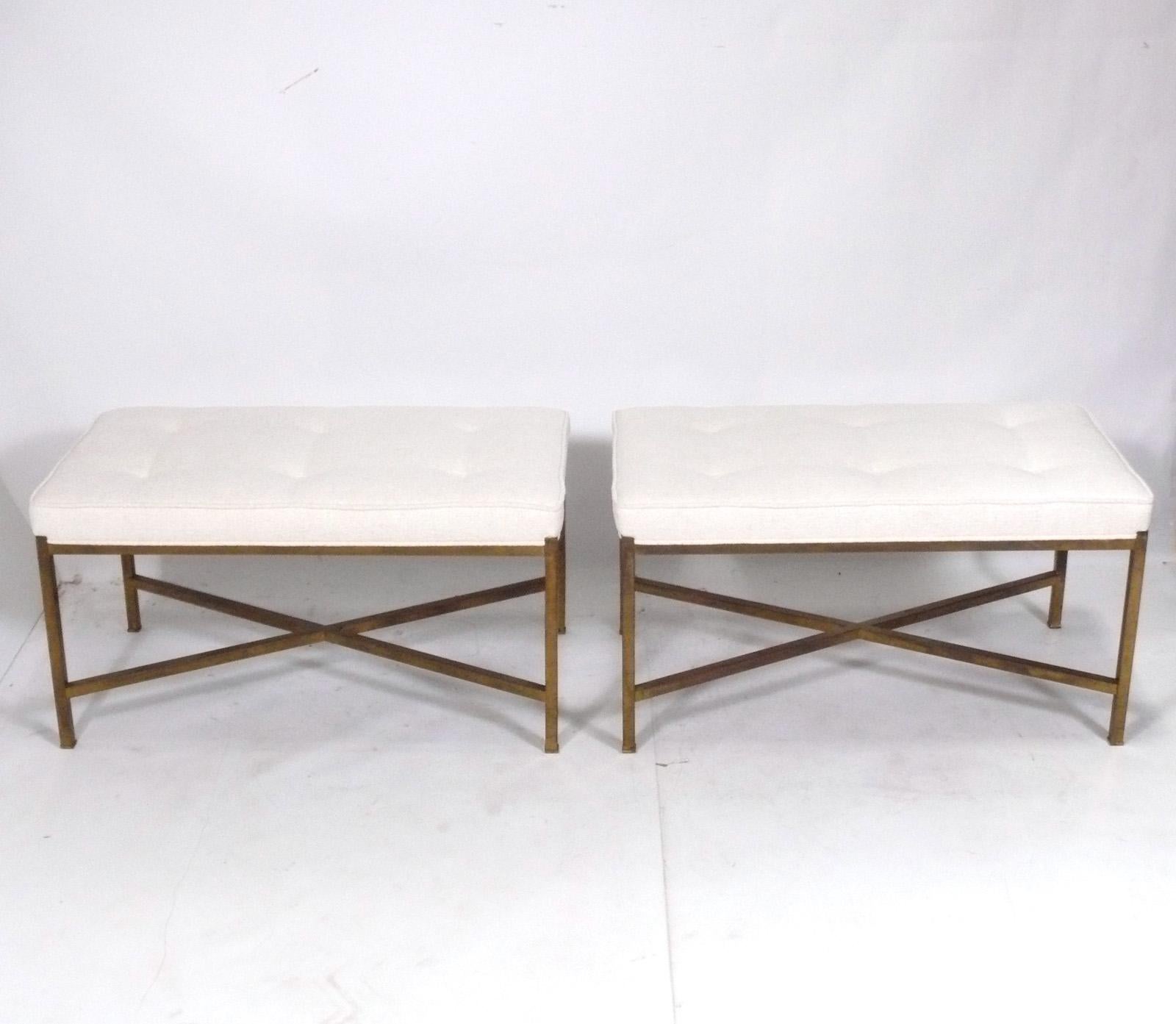 Selection of large scale sculptural X-based brass benches, in the manner of Paul Mccobb, American, circa 1950s. They retain their original distressed patina to the bases, and have been newly reupholstered in an ivory colored upholstery.