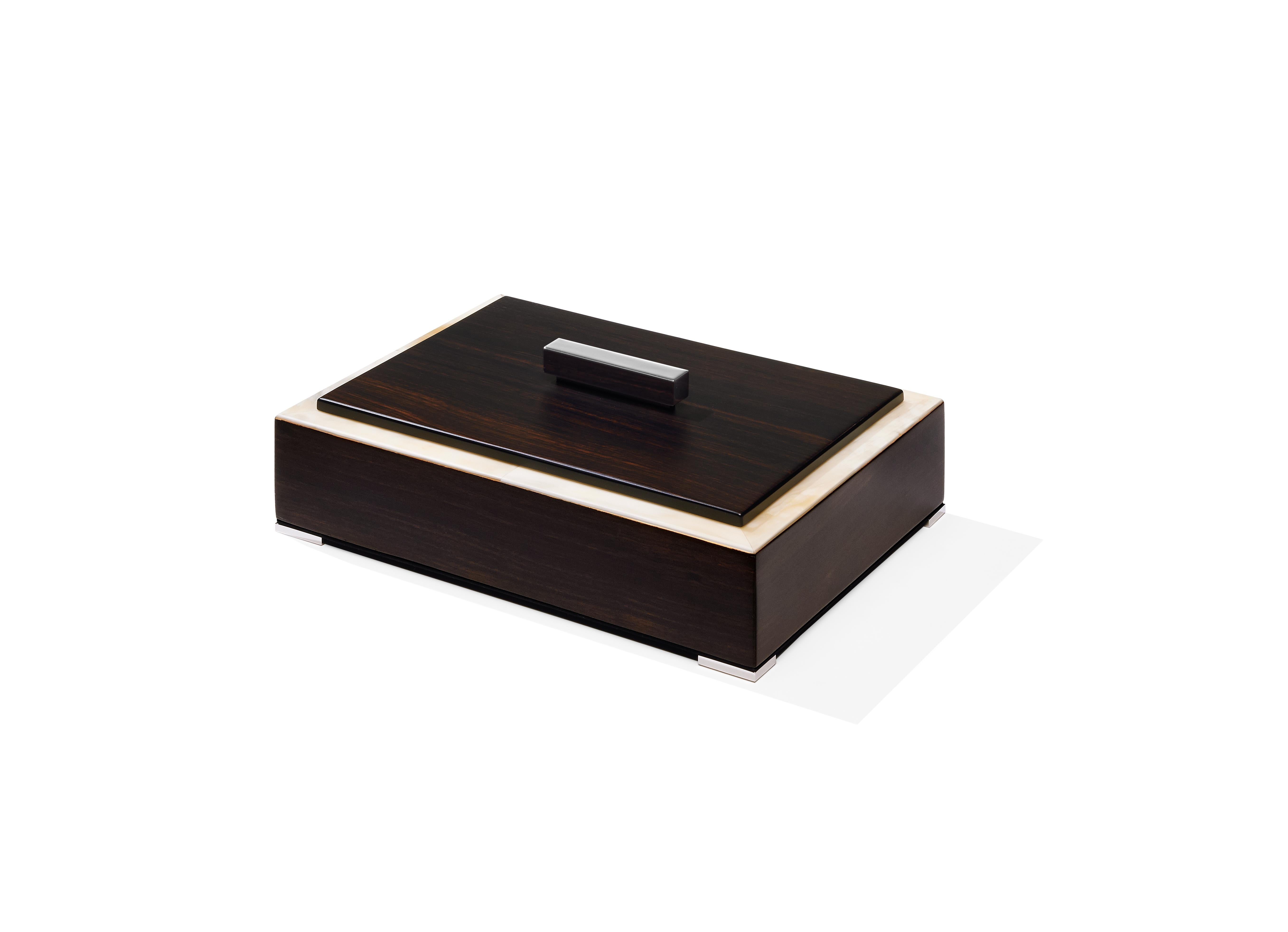 Distinguished by plush materials and essential lines, our Selene box showcases a rectangular wooden structure in Amara ebony veneer. Enhanced by an elegant edging in Matte Corno Italiano, this versatile box sits atop four feet in chromed brass and