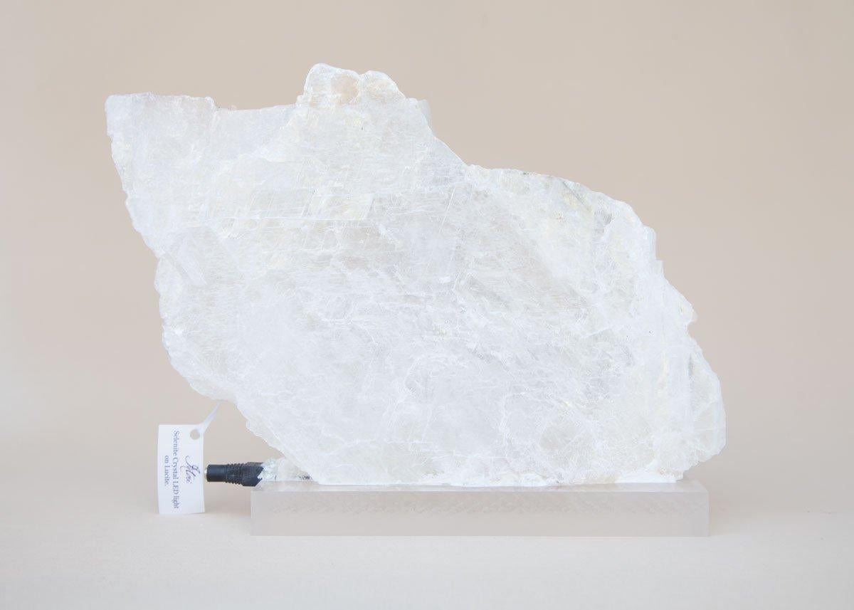 Selenite crystal LED light on Lucite. Selenite occurs as flattened and twinned crystals in the form of a slab. The LED light is inserted inside the crystal and is then mounted onto the Lucite base. When it turns on, the crystal illuminates in its