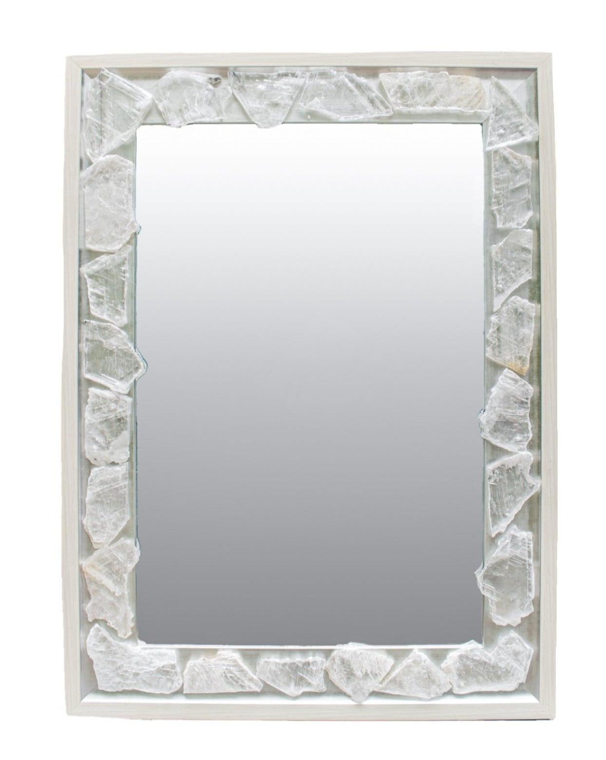 Selenite mirror with a silver and cream frame by Interi.

The mirror is adorned with selenite slices. Selenite is a crystallized form of Gypsum. It is comprised of striations which look like optical light fibers. Although selenite comes in many
