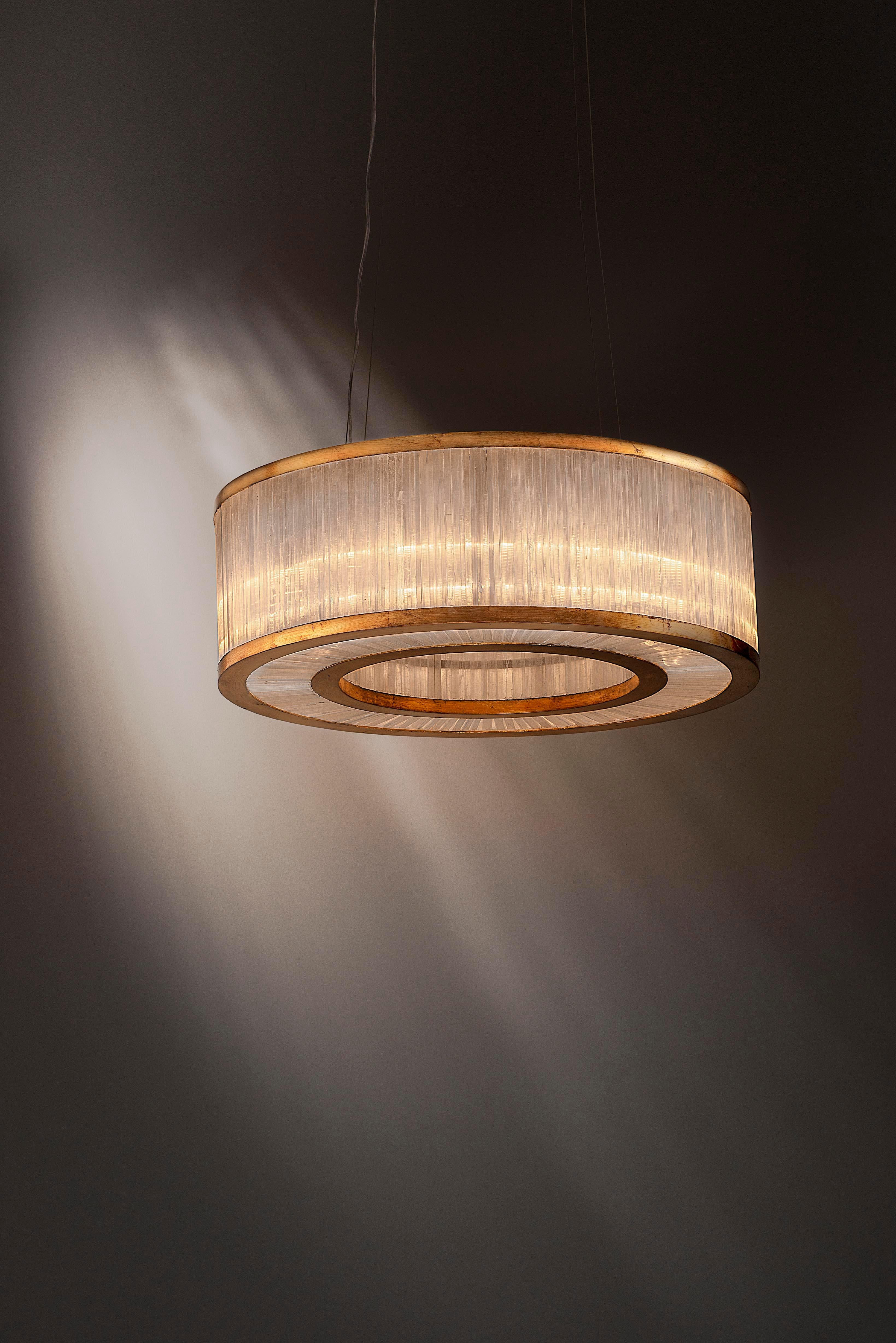 Selenite pendant lamp By Aver
Dimensions: D 76 x H 25 cm
Materials: Selenite, metal.
Also available: silver leaf, antique silver leaf, gold leaf, brass leaf, copper leaf, pink gold leaf.

Cylindrical pendant with a beautiful manual work done