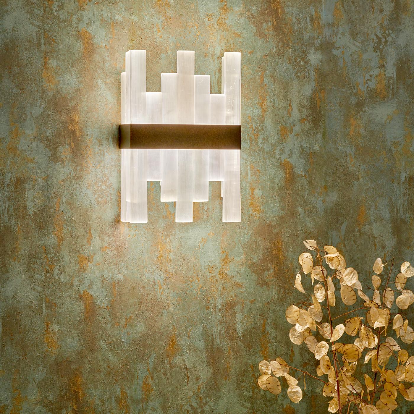 L'applique Selenor combina il fascino luminoso della selenite con la durata del bronzo. Le sue barre verticali di selenite catturano e diffondono la luce, creando incantevoli riflessi che aggiungono un tocco etereo a qualsiasi spazio. La texture