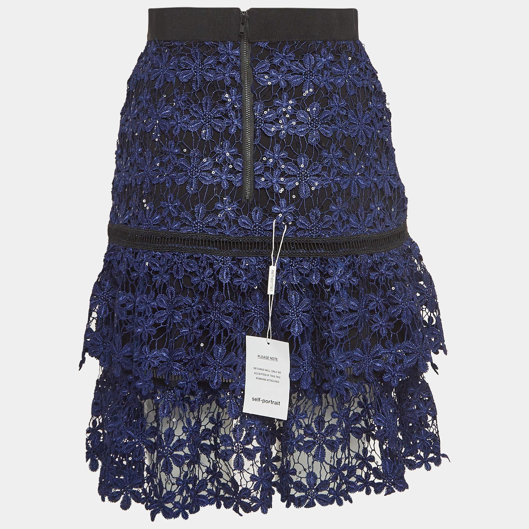 Capture the essence of timeless beauty in the Self-Portrait skirt. Delicate yet striking, this skirt boasts intricate floral guipure lace adorned with shimmering sequin embellishments. Its tiered design adds dimension and movement, while the soft
