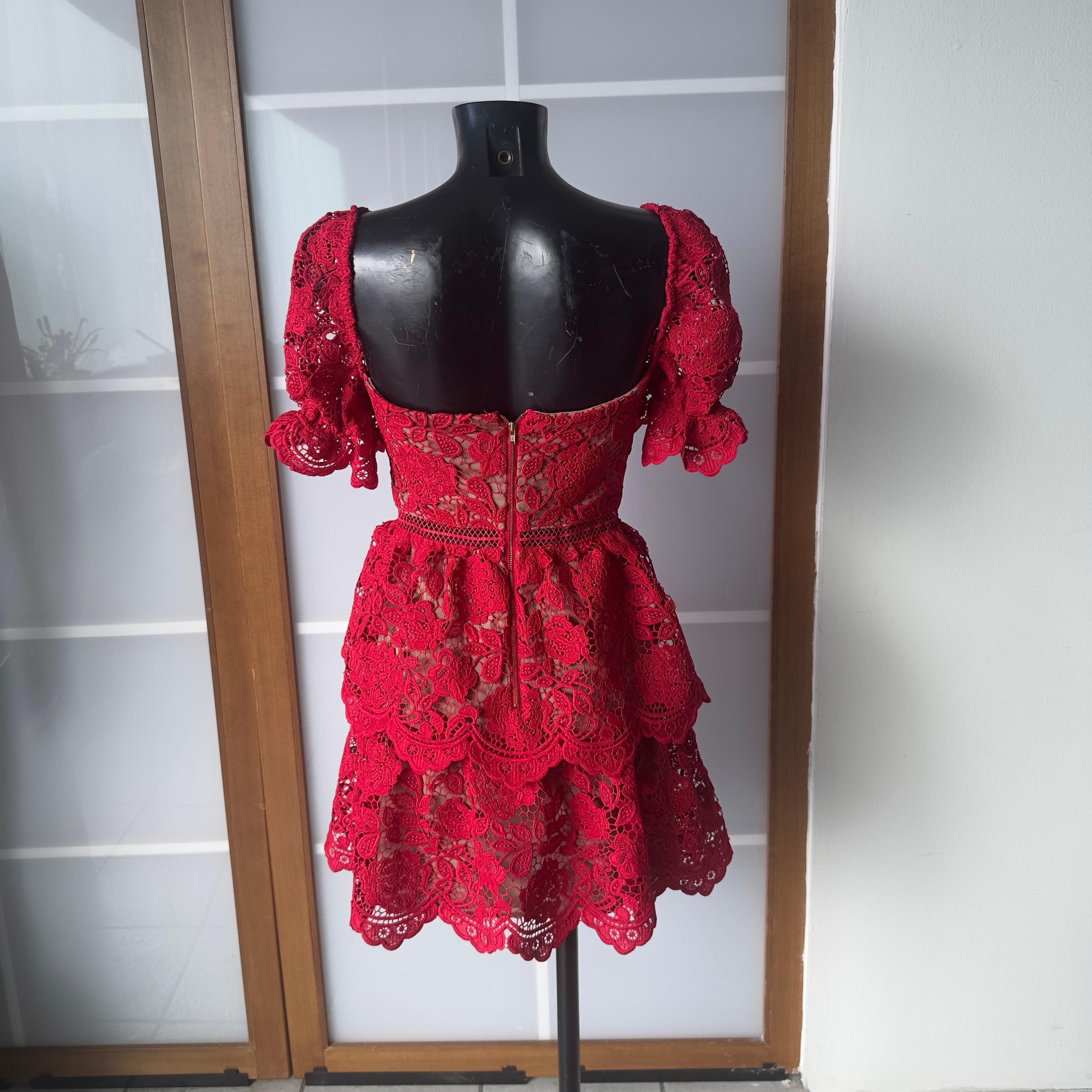 Intrigante vestido de Self-Portrait, modelo Fuchsia Flower Lace Mini Dress de la colección Primavera/Verano 2020, confeccionado en refinado encaje floral rojo con detalles cut out y forro nude. El diseño presenta un corpiño estructurado con escote