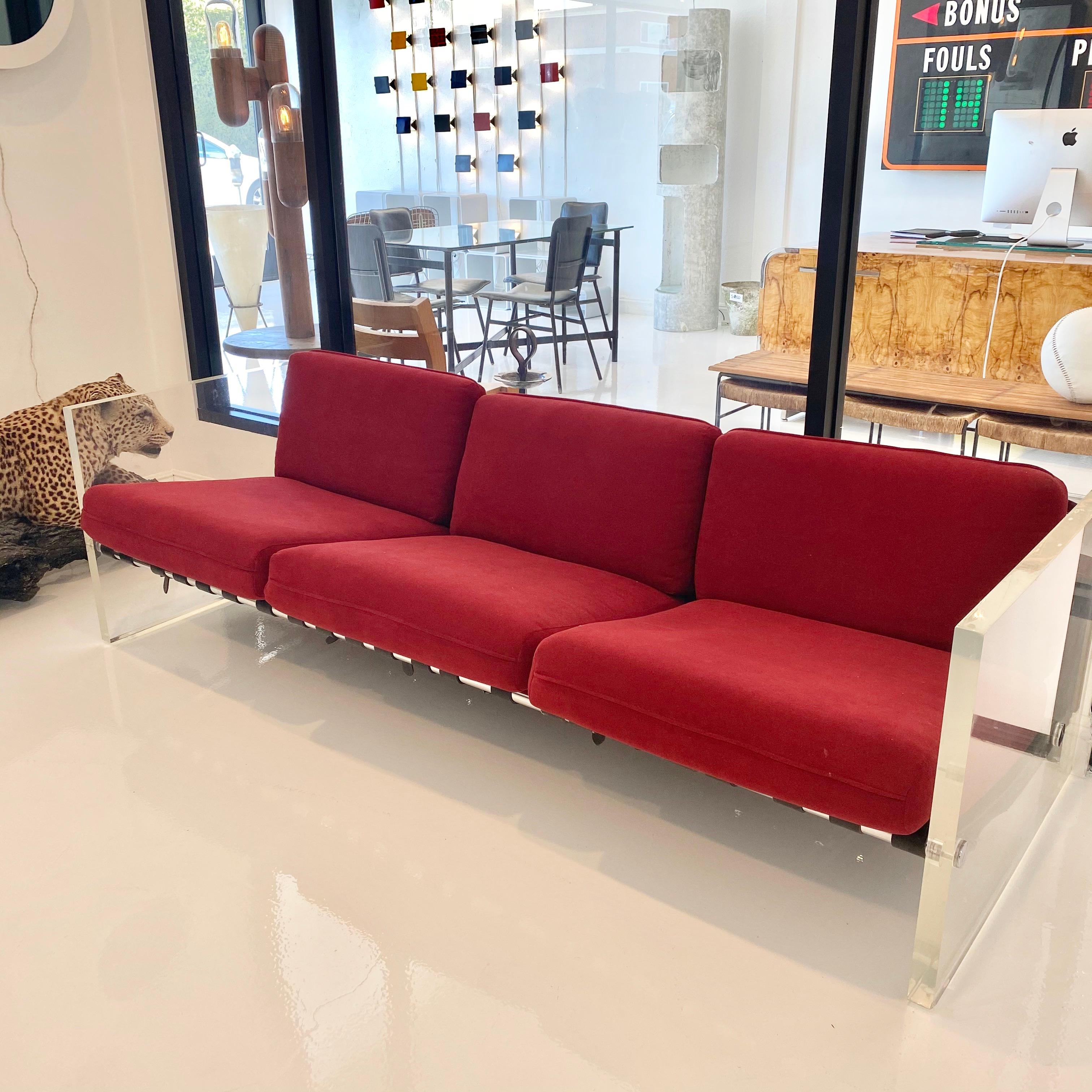 Fantastic Lucite sofa by Selig with black leather straps. There are three long nickel bars running through the length of the sofa holding the black leather seat straps and back cushion straps. The bars are capped by large nickel screws. Extremely