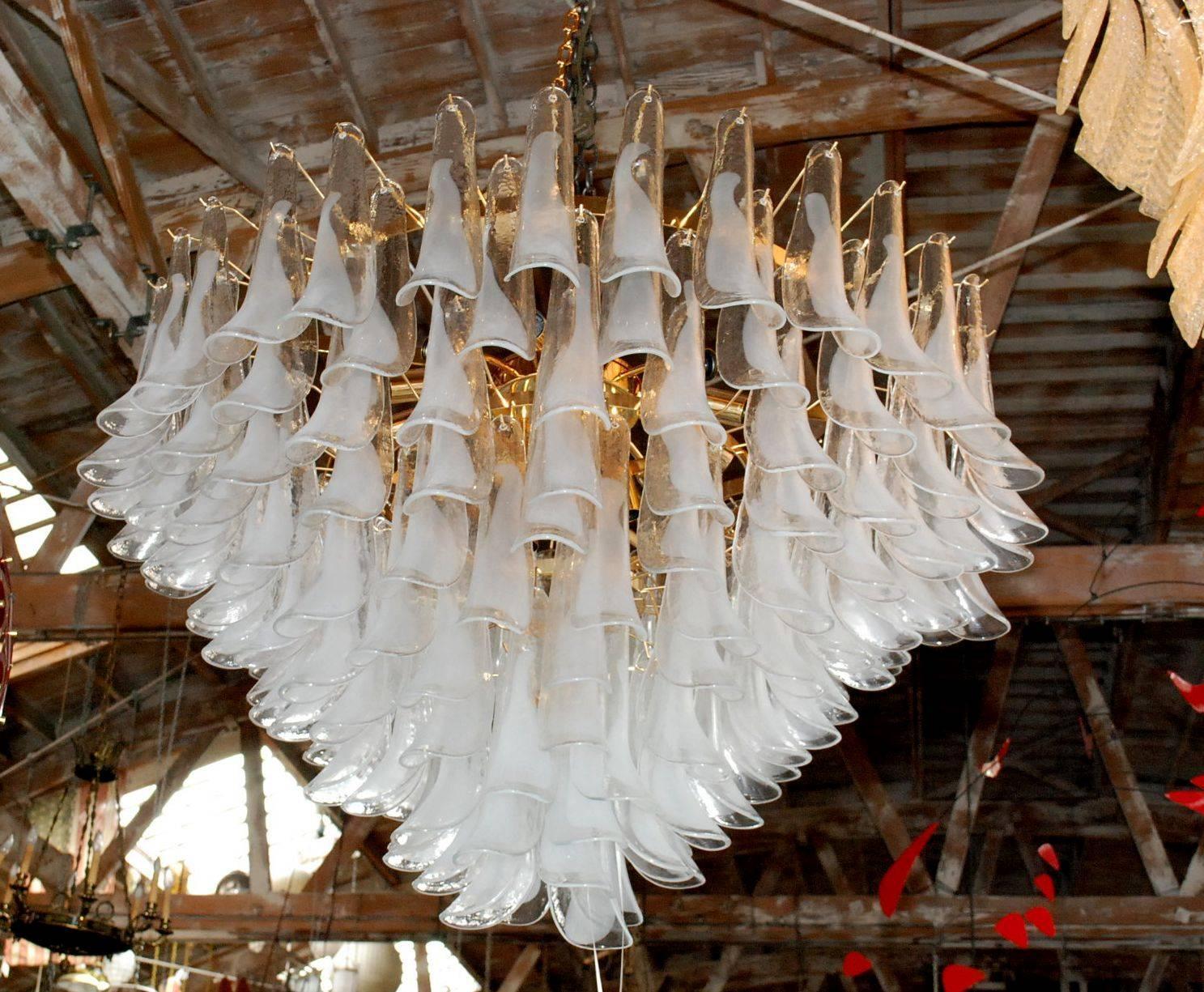 Lampadario italiano con petali in vetro di Murano bianco chiaro e lattiginoso montati su una cornice con finitura oro 24 k / Disegnato da Fabio Bergomi per Fabio Ltd, ispirato da Mazzega / Made in Italy
21 luci / tipo E26 o E27 / max 60W