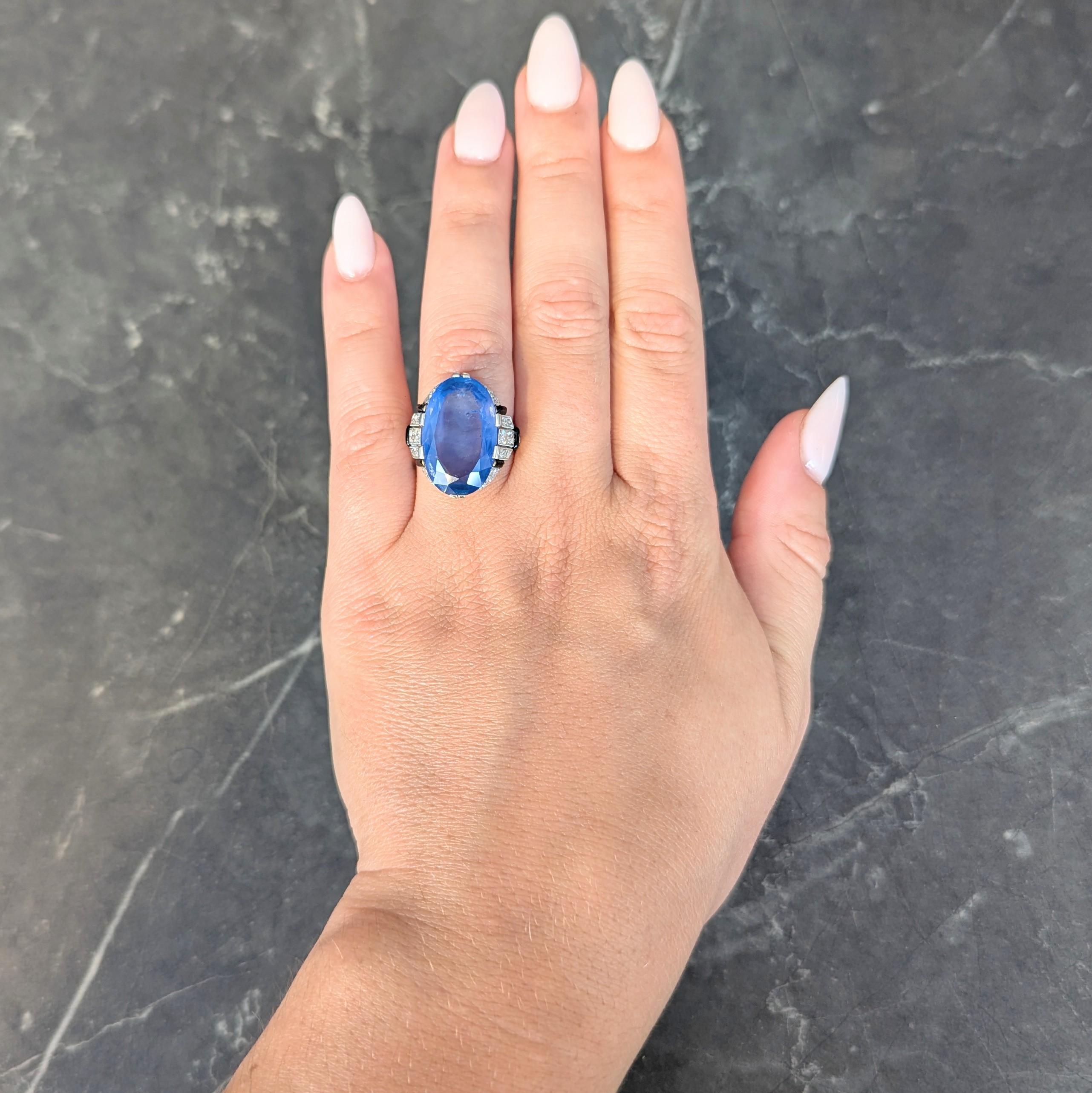 Centering an oval cut sapphire weighing 15.10 carats - transparent light blue in color
Natural Ceylon (Sri Lankan) in origin and displaying no indications of heat treatment
Set with split and wide prongs in pierced basket and flanked by cathedral