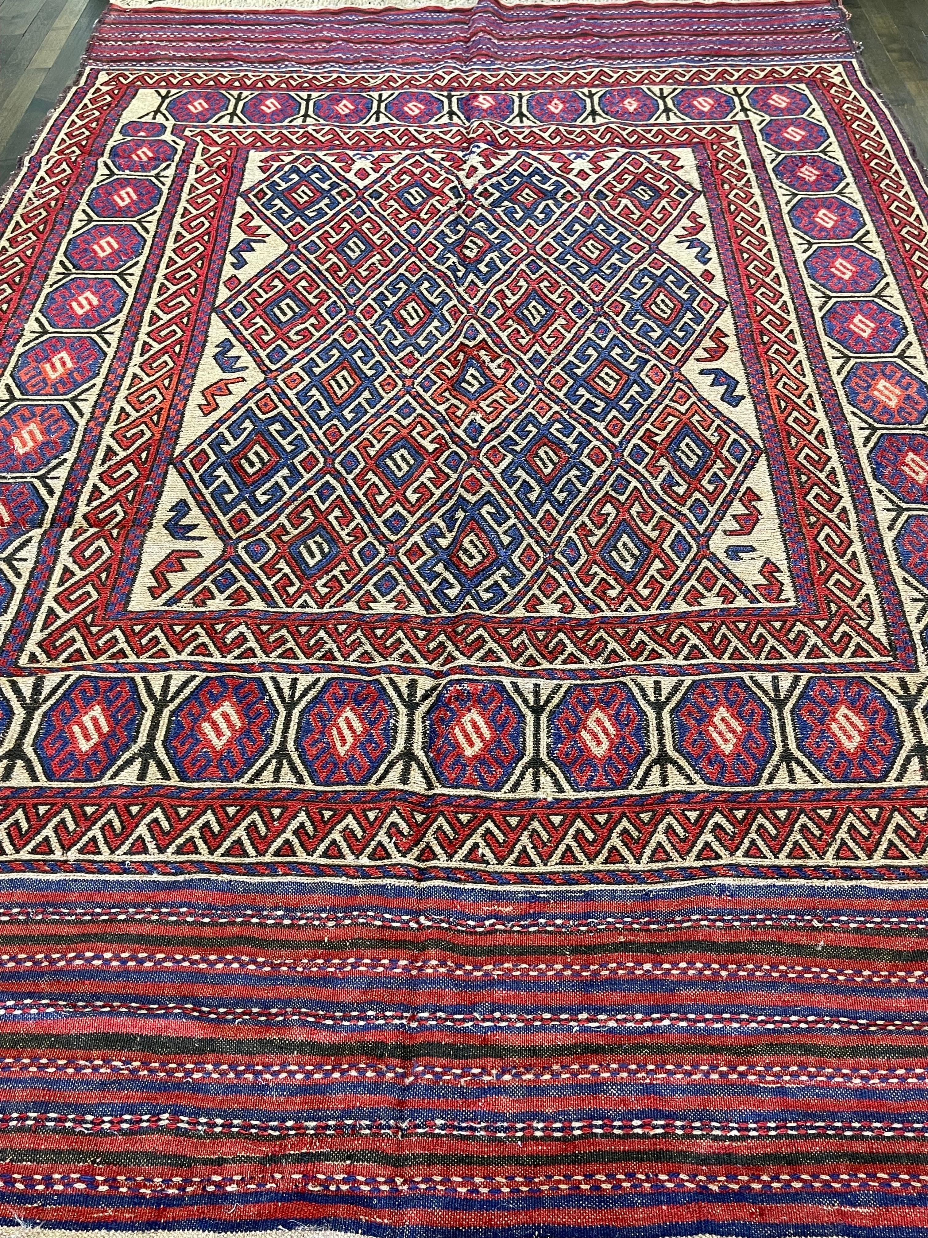 A beautiful overall design flat weave Kilim,this rug is created by the Turkman Tribe.With color palette of purple red,sky blue on a pale cream field. The carpet is decorated with repeated checker-edged diamonds filled with Ersary motifs. The rug is