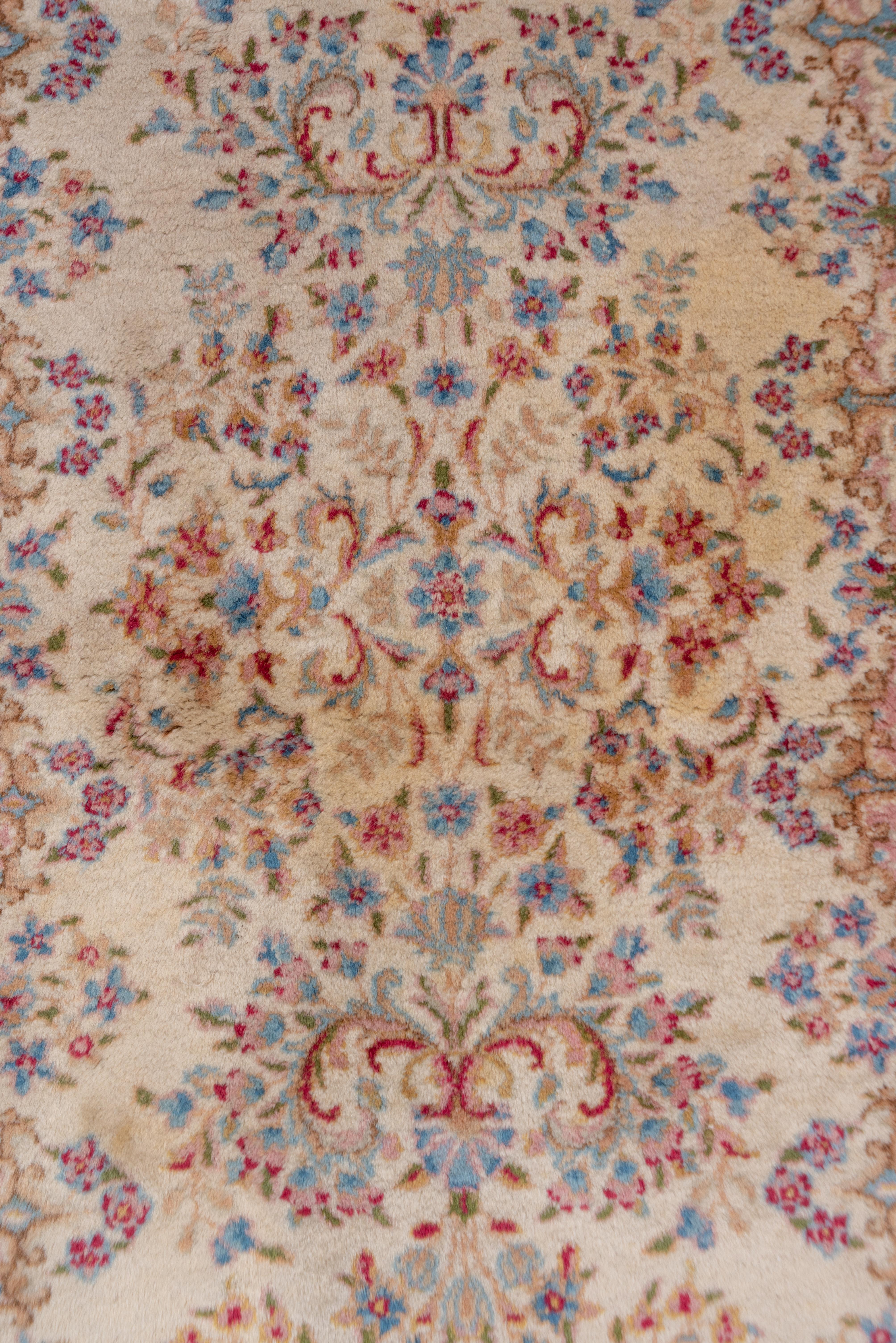 This full pile SE Persian runner with an ivory ground, broken border and tones of warm red, powder blue, light blue, rust and goldenrod displays vases and flowers alternating with pure flower groups. The dyes are all natural on this airy carpet