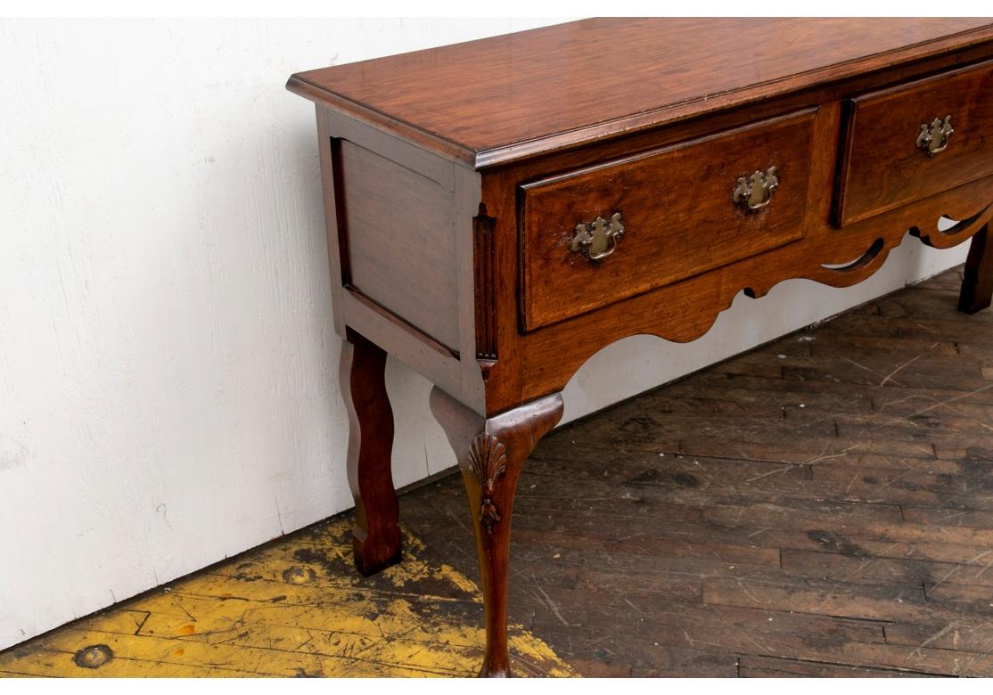A fine server with an overhanging top with carved edge. The apron with three deep drawers with fine brass bat wing bales and an unusual openwork scalloped lower frame. Raised on carved front legs with palmetttes on the knees and pad feet, and square