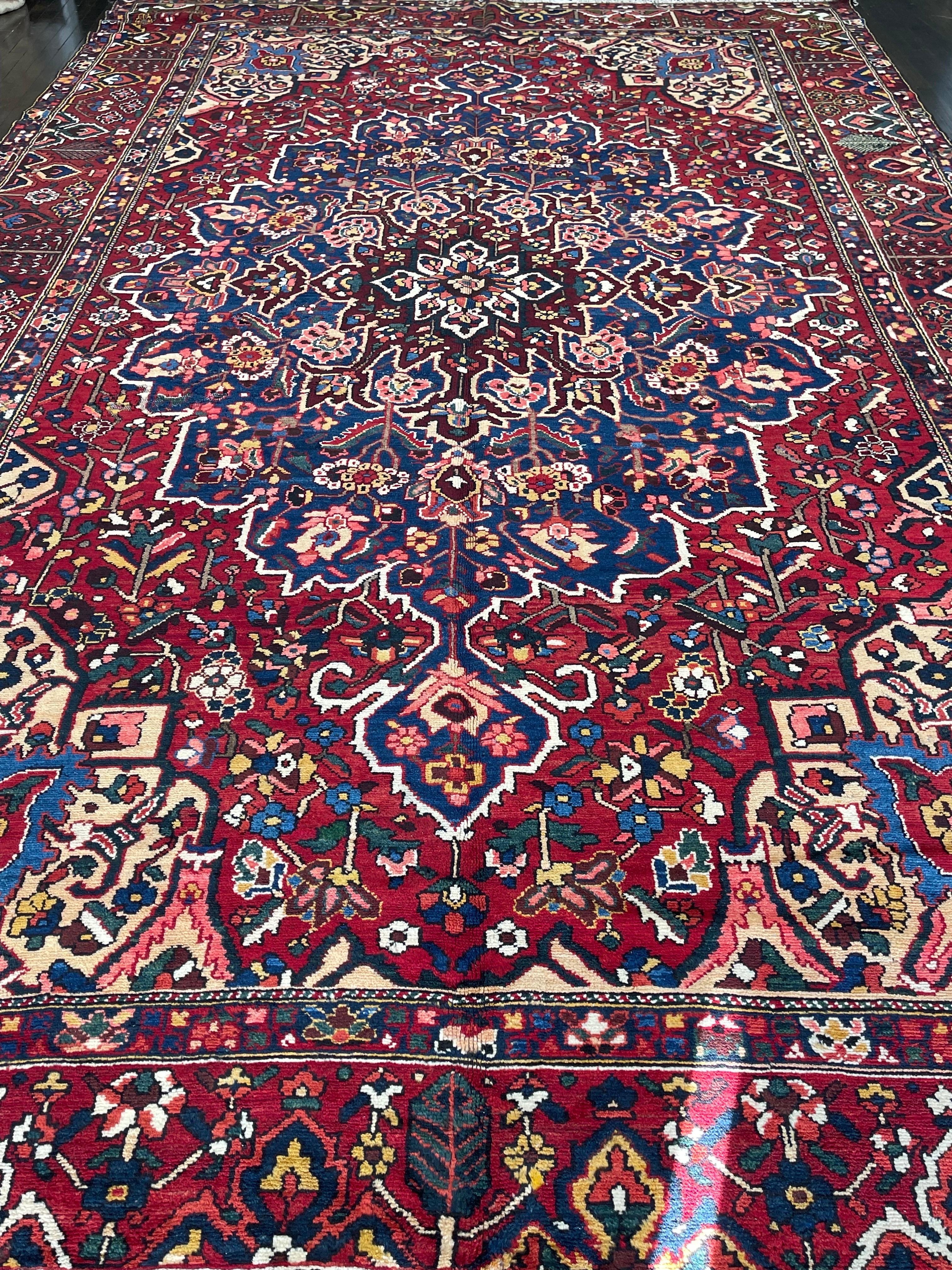Very handsome tribal Bakhtiari carpet featuring a large medallion on a blue field surrounded by an orange/red border decorated with rosette and cypress trees all in bright brilliant colors. The Bakhtiari tribe settled on the Zagros mountains and