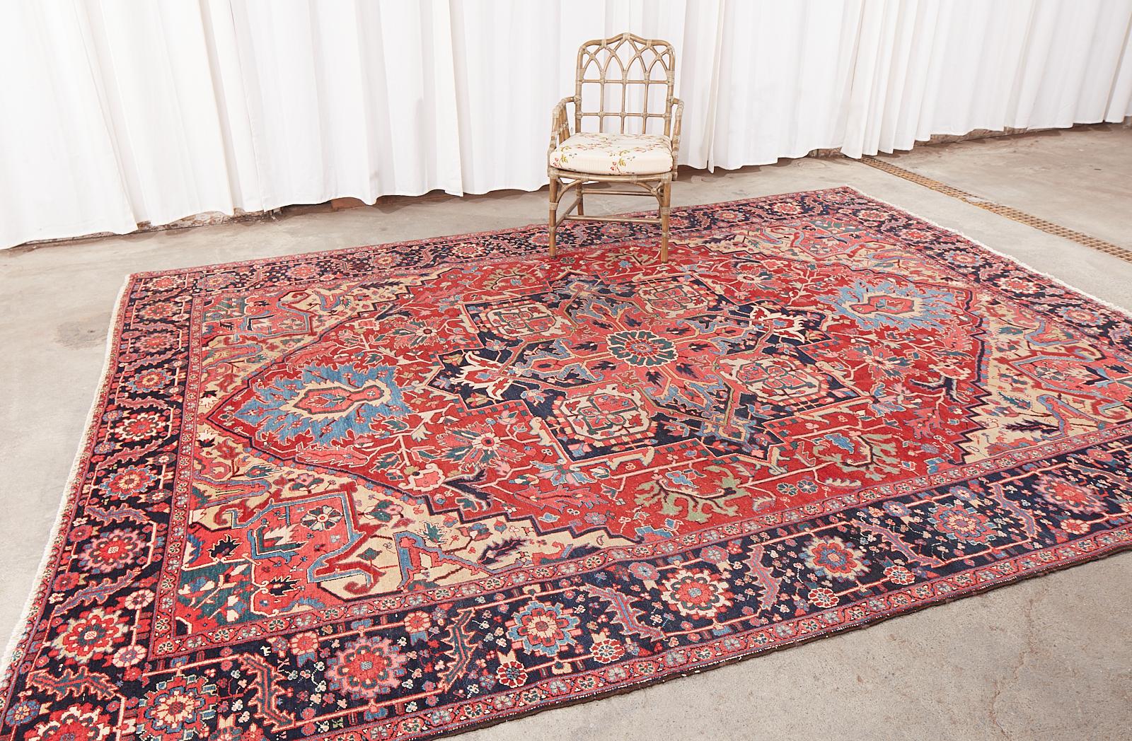 Traditionally styled semi-antique 20th century Persian Heriz rug crafted from hand-knotted wool with a cotton warp. The rug features a large multi-faceted star medallion in a red field with fascinating electric blue palmette designs. The field has