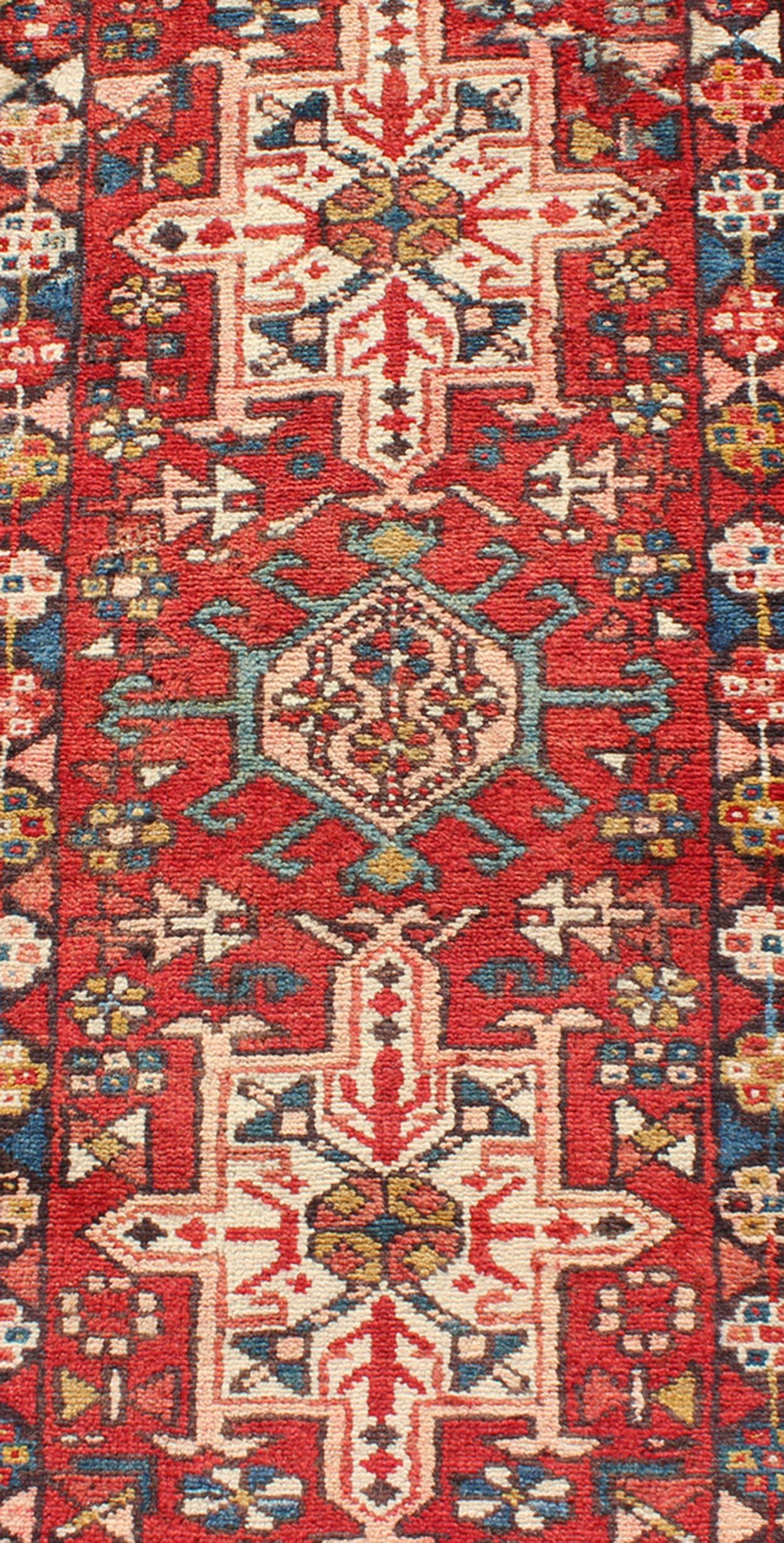 Ce tapis de course semi-ancien Karadjeh, tissé à la main au milieu du 20e siècle, présente un champ de couleur rouge imprégné de médaillons ornés. Une bordure à plusieurs niveaux magnifiquement dessinée entoure la totalité de la pièce.