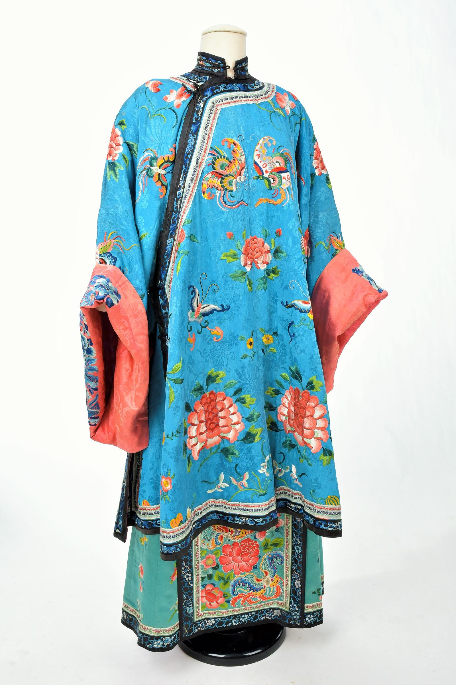 Late 19th century, early 20th century
China

Exceptional Semi-Formal dress and skirt of a Manchu woman, China late 19th century. Celestial blue damask silk crepe dress embroidered with peking stitch silk peonies and multicoloured butterflies. Lining
