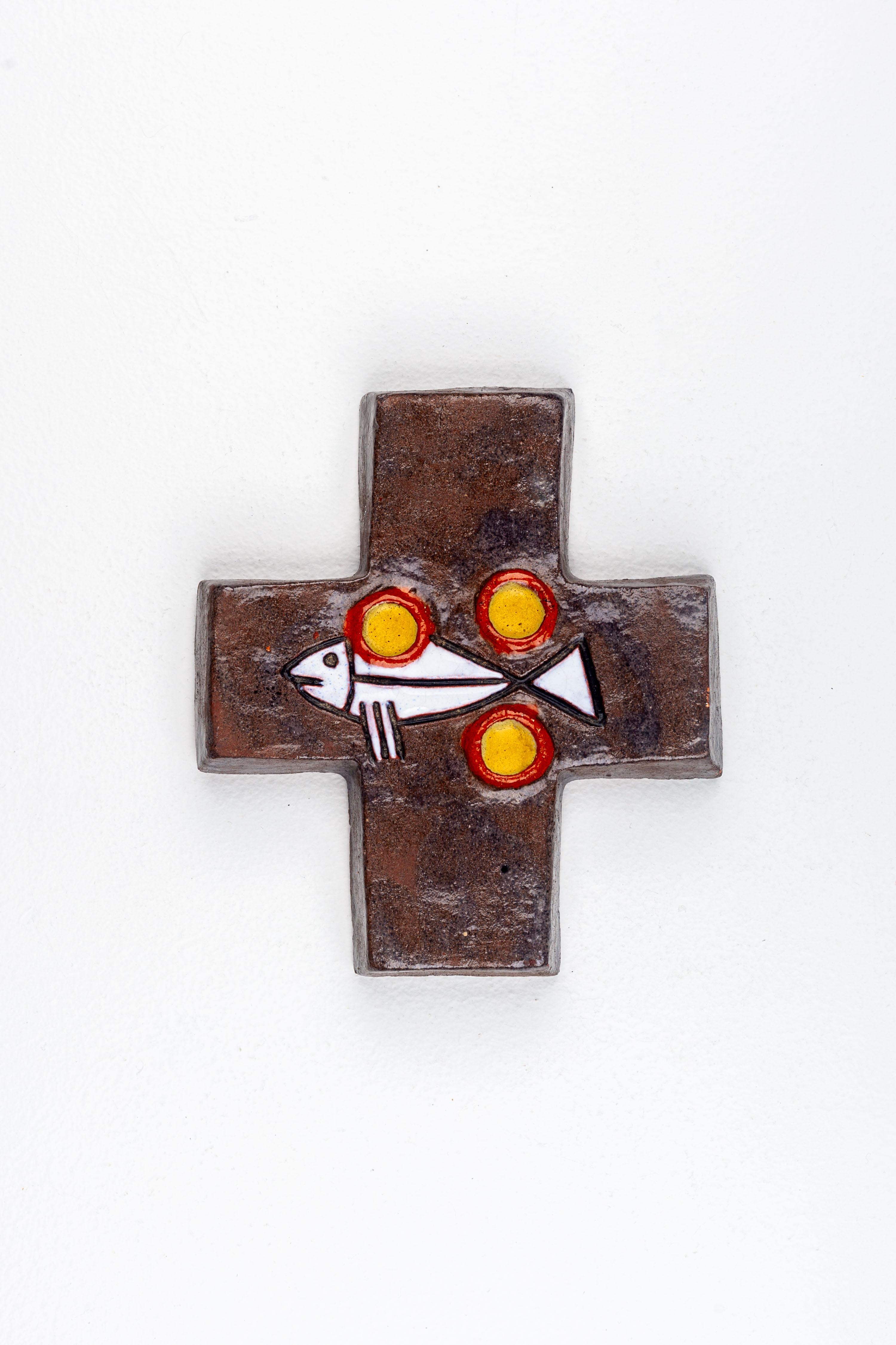 This mid-century modern ceramic cross is a notable piece of religious art that carries the symbolic weight of its imagery through the medium of studio pottery. Handcrafted by European artisans, it is characterized by a tactile surface finished in a