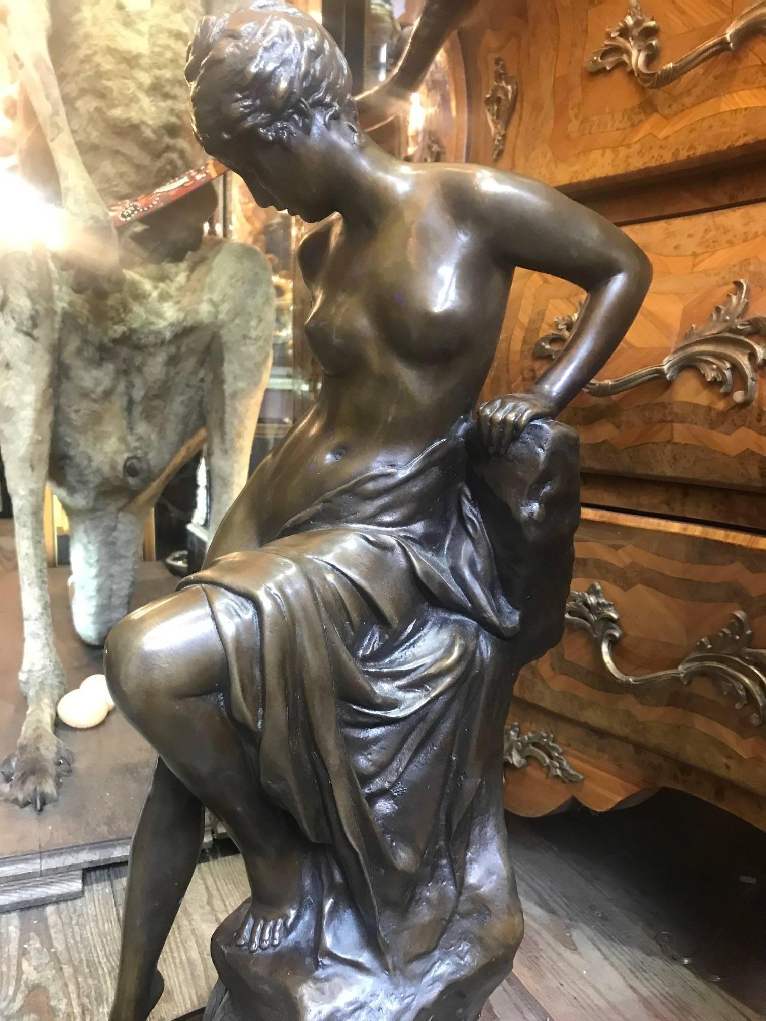 Semi nude 19th century bronze statue of a woman seated on a rock. Nouveau figurine.