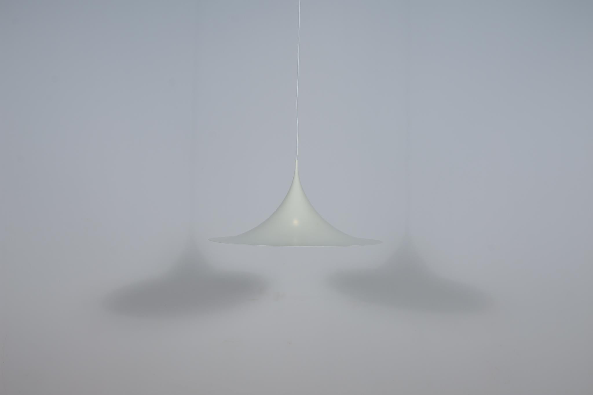 Die Pendelleuchte wurde 1967 von Claus Bonderup und Torsten Thorup für Fog & Morup entworfen. Die Hängelampe Semi hat eine schöne, raffinierte und organische Form. Die Leuchte ist aus lackiertem Aluminium gefertigt. Lampe  wurde in vielen Größen