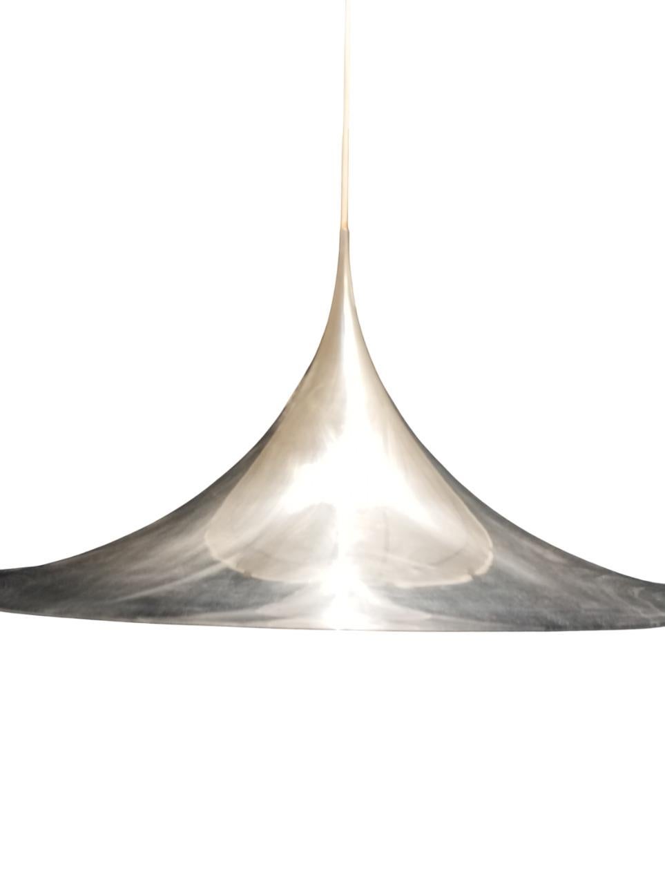 La Semi Pendant Lamp è un'iconica lampada a sospensione disegnata da Claus Bonderup e Torsten Thorup per la rinomata azienda danese Fog & Mørup negli anni '70. Questo pezzo di design riflette perfettamente lo stile scandinavo di quel periodo.
Con un