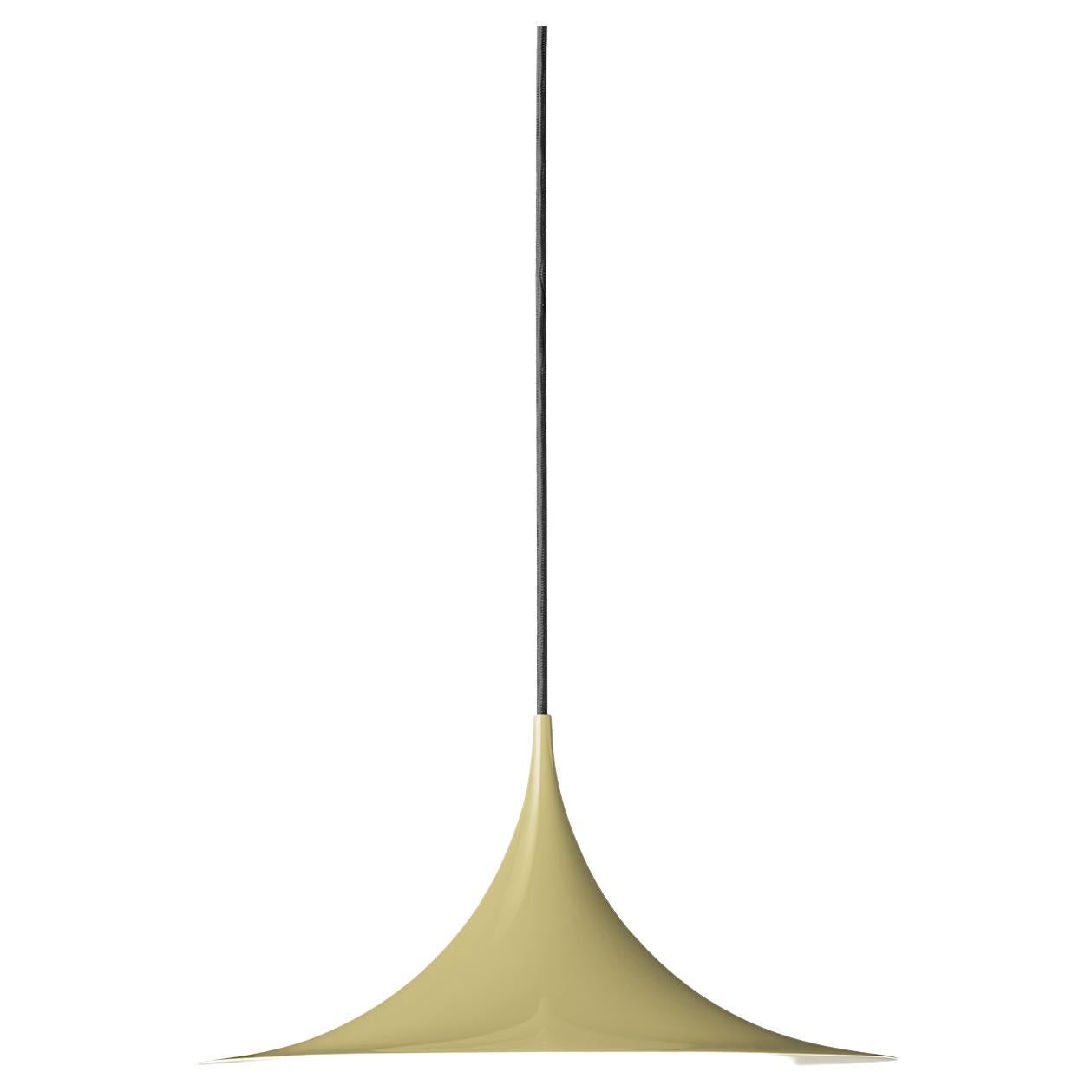Le Semi Pendant est une lampe suspendue unique, basée sur deux quarts de cercle assemblés dos à dos. Son abat-jour en métal émaillé en forme d'arche crée une lumière diffuse en forme de cône, idéale au-dessus d'une table à manger ou d'un plan de