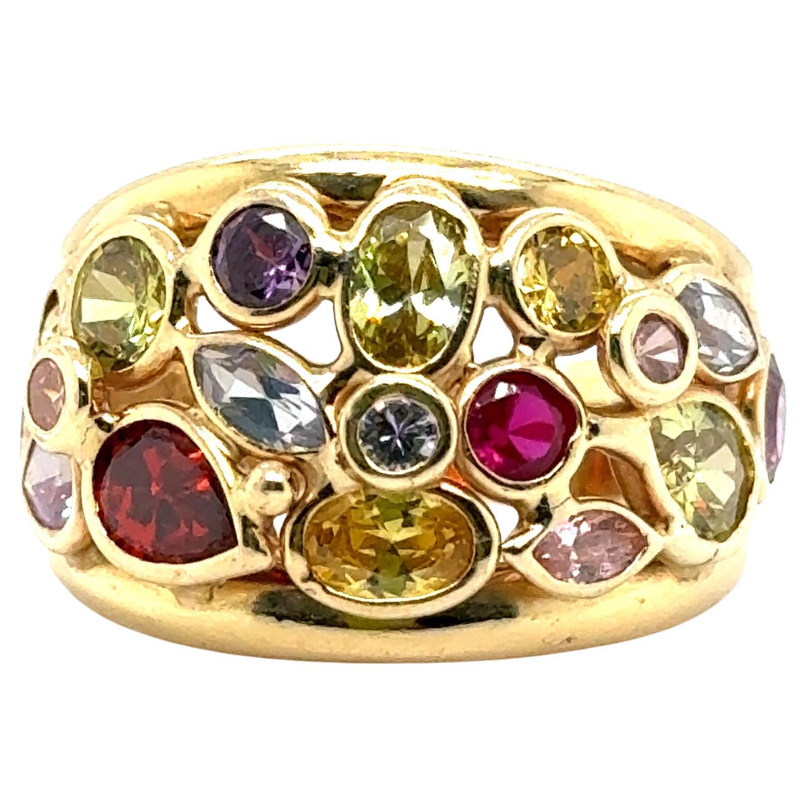 Eleganter Ring aus 14k Gelbgold. Dieser Bombenring hat oben ein breites Band, das nach unten hin schmaler wird. Die obere Hälfte misst 16 mm und die untere 5 mm.
Dieses Design präsentiert eine Reihe von farbenfrohen, geformten Edelsteinen, die alle