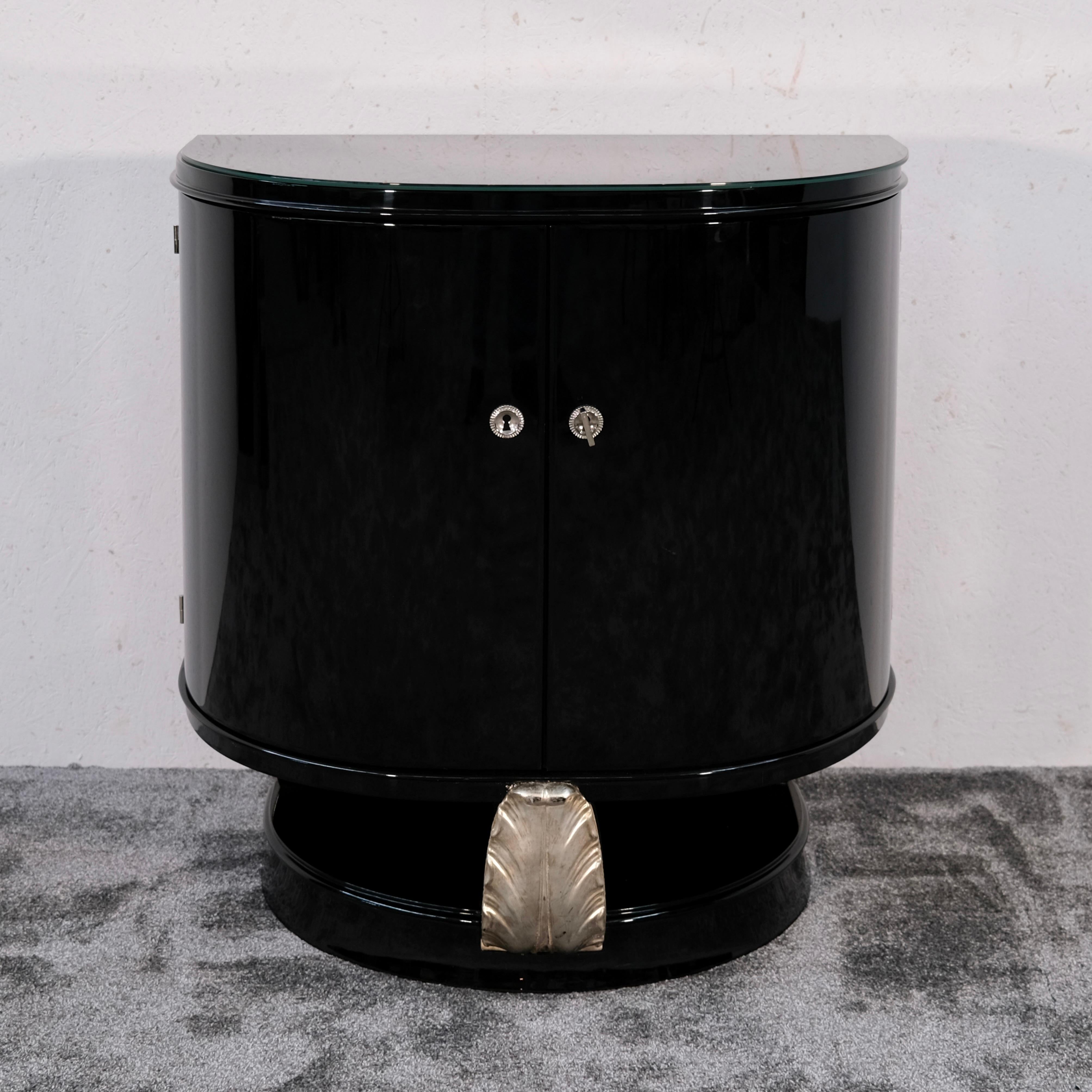 This stunning Art Deco bar cabinet from France, dating to the 1930s, enchants with its rare semicircular silhouette and luxurious black piano lacquer finish. With its compact proportions and sculptural form, this original piece is both decorative