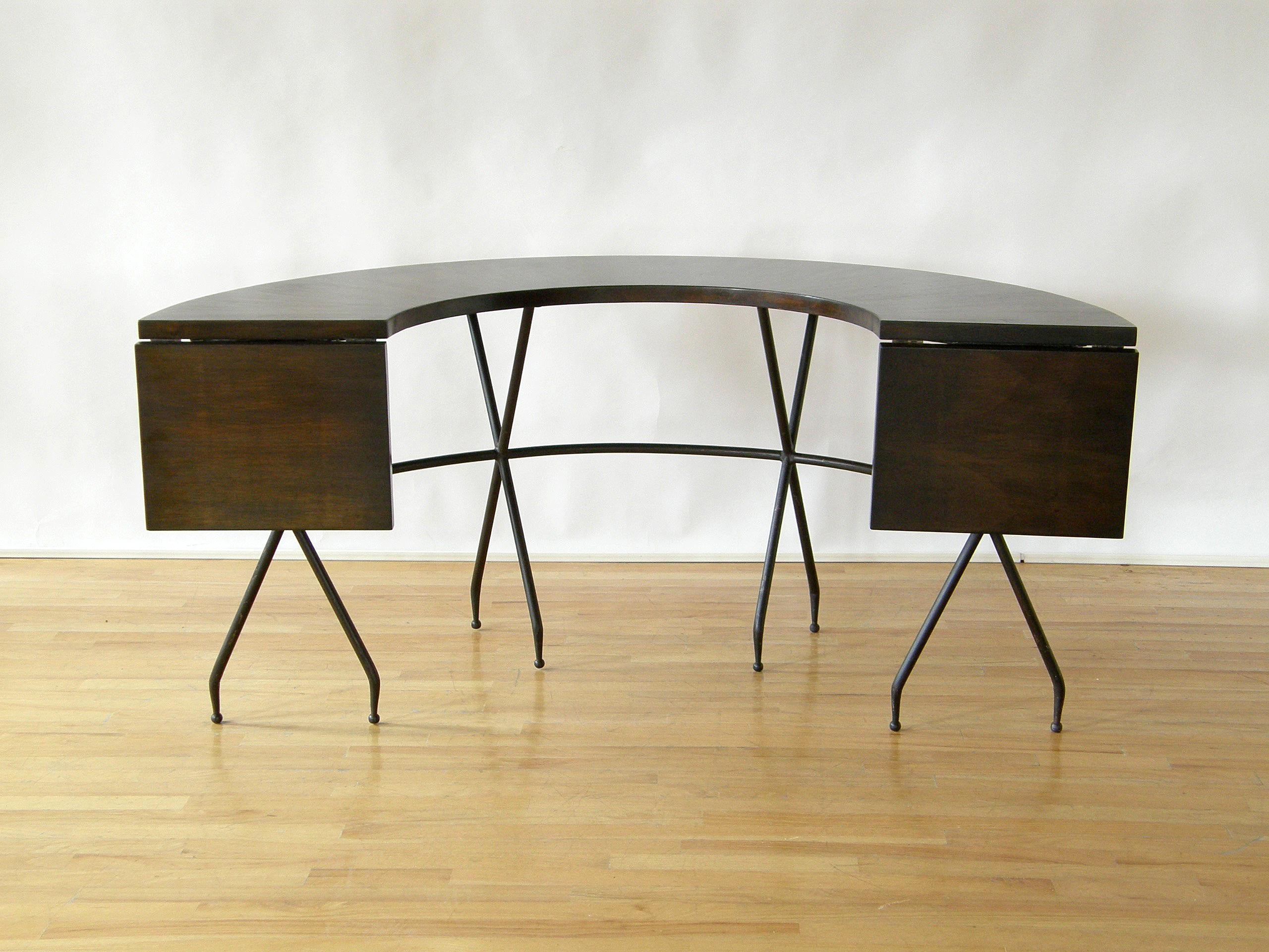 This semicircular hunt style table is a modern take on a traditional form. It has a horseshoe shaped top with drop leaves on each end to extend the working surface. The black painted steel (or iron?) base has four 
