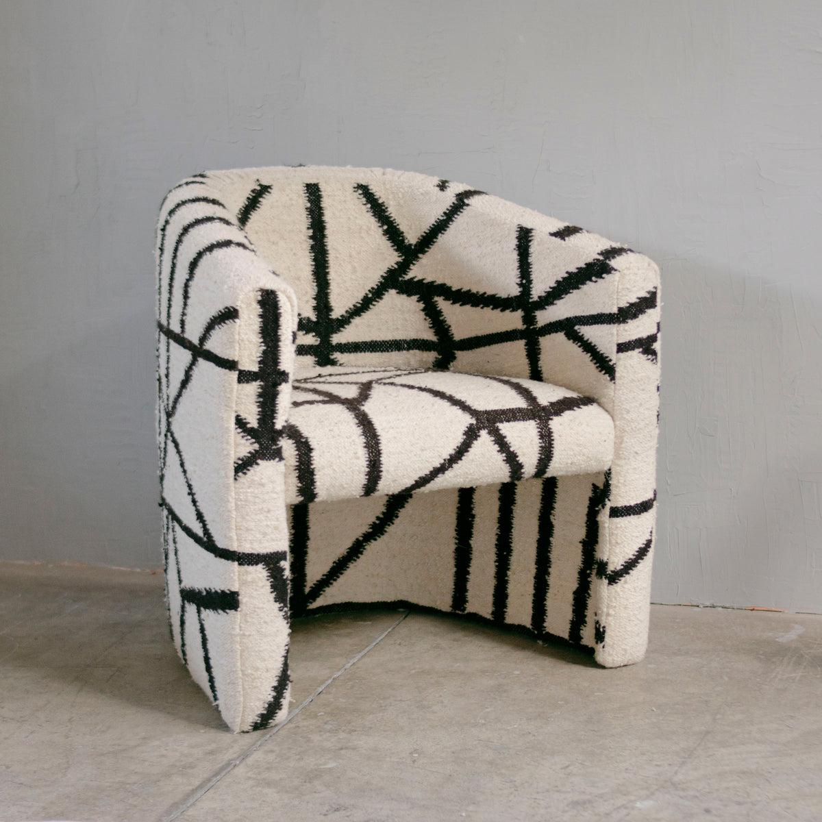 Der Senderos Wool Chair ist ein einzigartiges und kreativ gestaltetes Möbelstück, das das Zusammenspiel der Linien erforscht. Dieser Stuhl wird von Kunsthandwerkern in Momostenango, Guatemala, hergestellt, die jedes Stück auf einem Pedalwebstuhl aus
