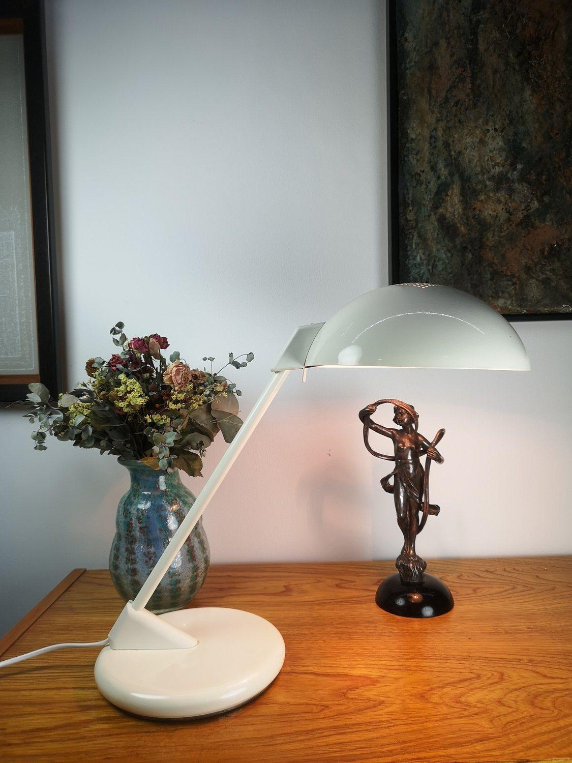 Seneca table lamp with a round, white metal base and a perforated adjustable lamp shade. Thanks to its functional design, it easily adapts to any work area or tabletop that requires lighting. Available in excellent condition.