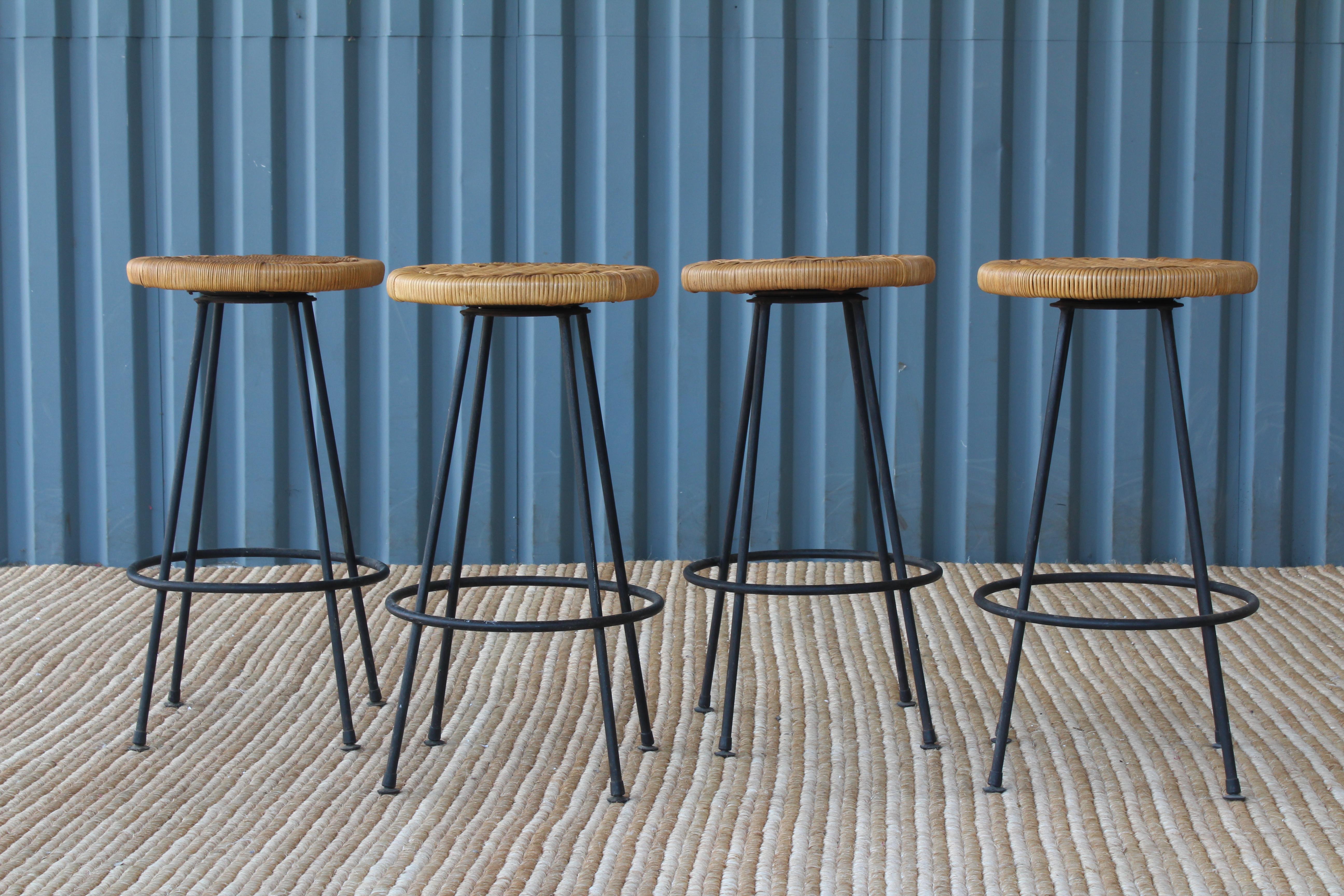 Set of four 1950s iron bar stools with rattan seats. Seats have new rattan and swivel. Sold as a set.