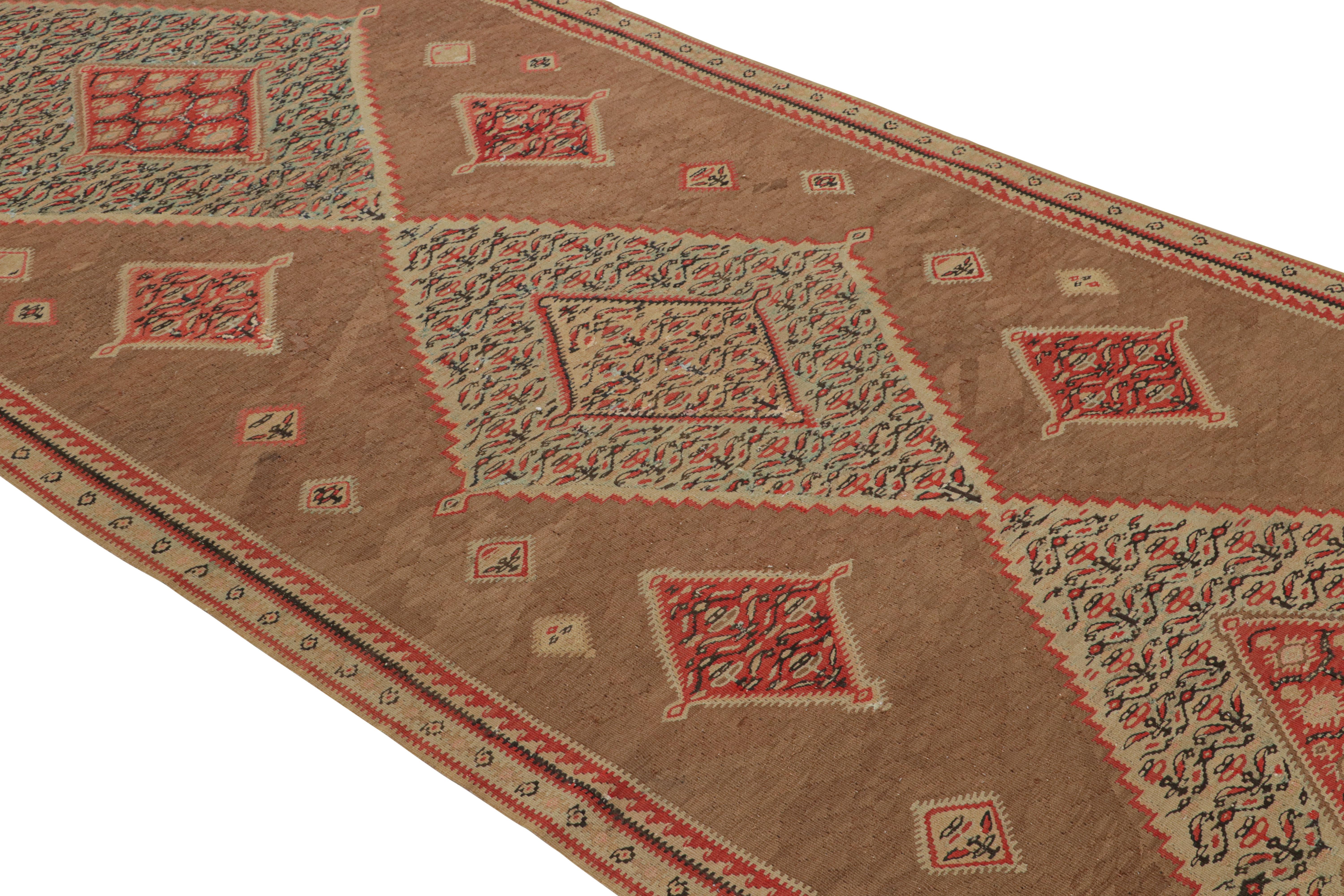 Dieser aus Persien stammende (antike/vintage) handgeknüpfte Senneh-Perserkelim aus Wolle weist eine perfekt gespiegelte Reihe von Rautenmotiven auf, die die rustikalen roten und beige-braunen Farbtöne in seinem Feld und seiner Bordüre wieder