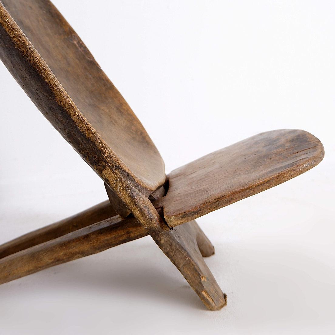 Chaise africaine en bois sculptée à la main avec une belle patine brun foncé. Cette chaise pliante, composée de deux pièces qui s'emboîtent, est fabriquée à partir d'un seul morceau de bois d'ébénisterie d'Afrique de l'Ouest. Également appelée