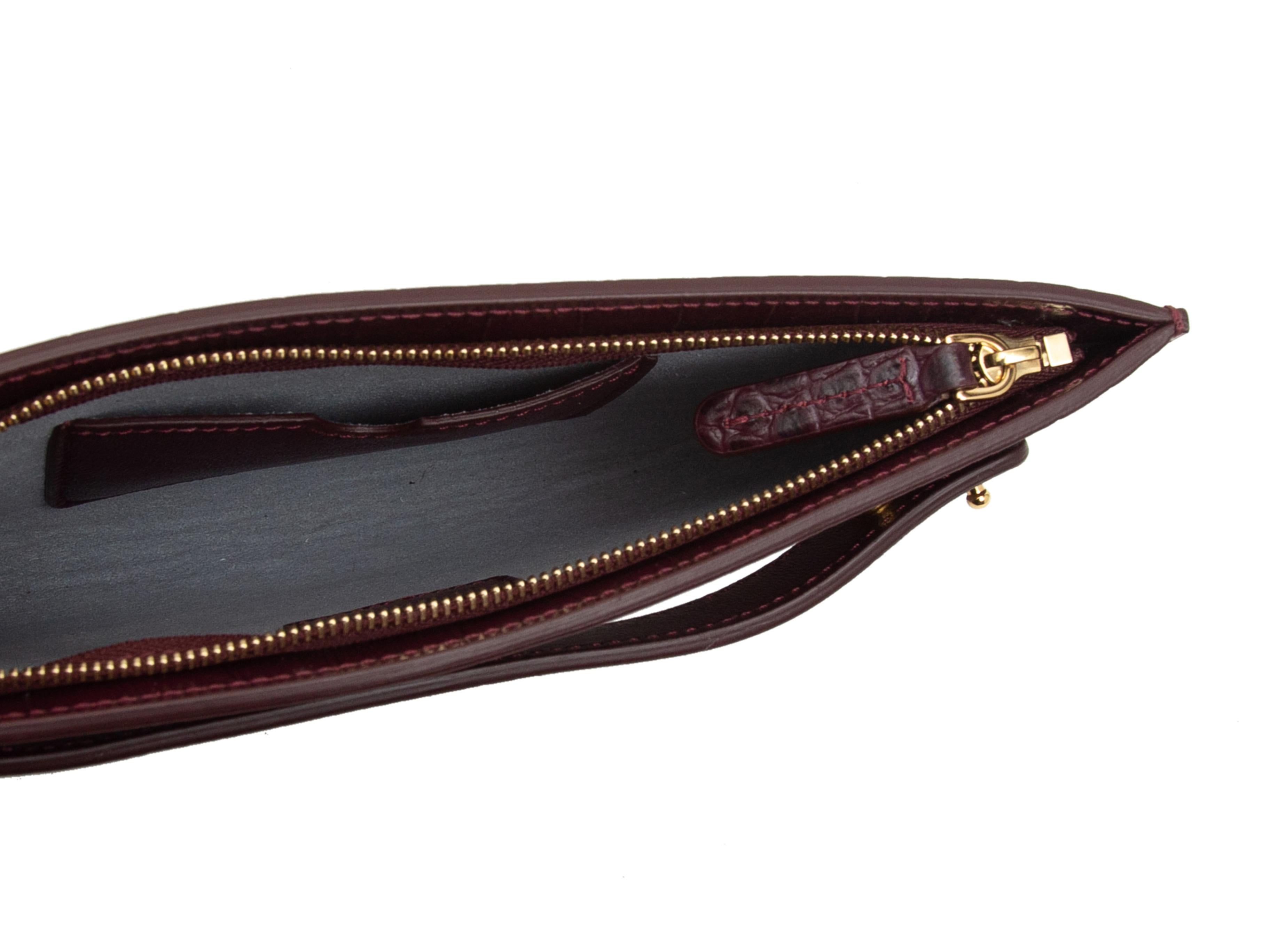 Product details: Burgundy 'Dragon' embossed leather Bracelet Pouch by Senreve. Gold-tone hardware. Zip closure at top. 4.75