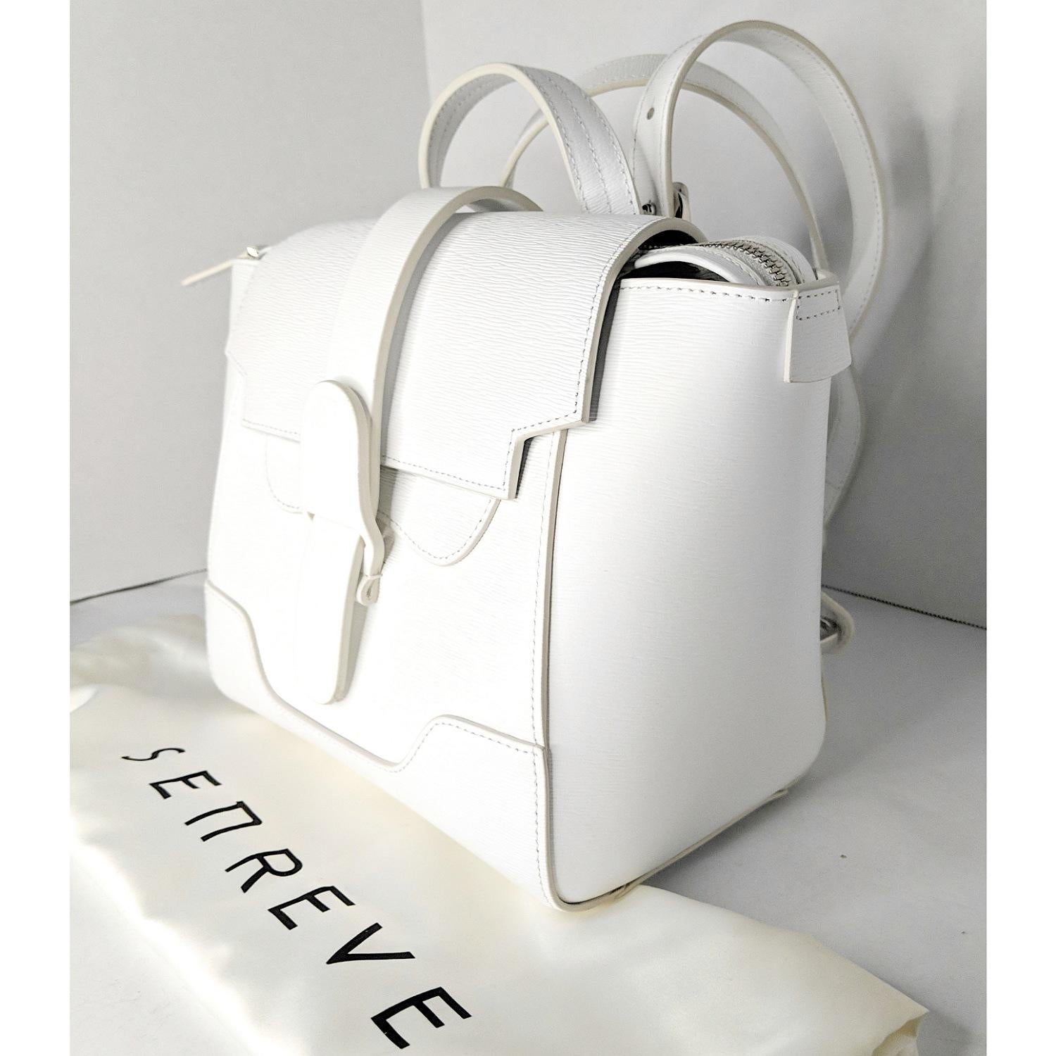 This stylish Senreve Mini Maestra Backpack is made of 100% genuine pebbled Calfskin leather in White with silver-tone hardware. Featuring adjustable straps that can be worn as a either a backpack or as a cross body bag. Secured by a flap closure