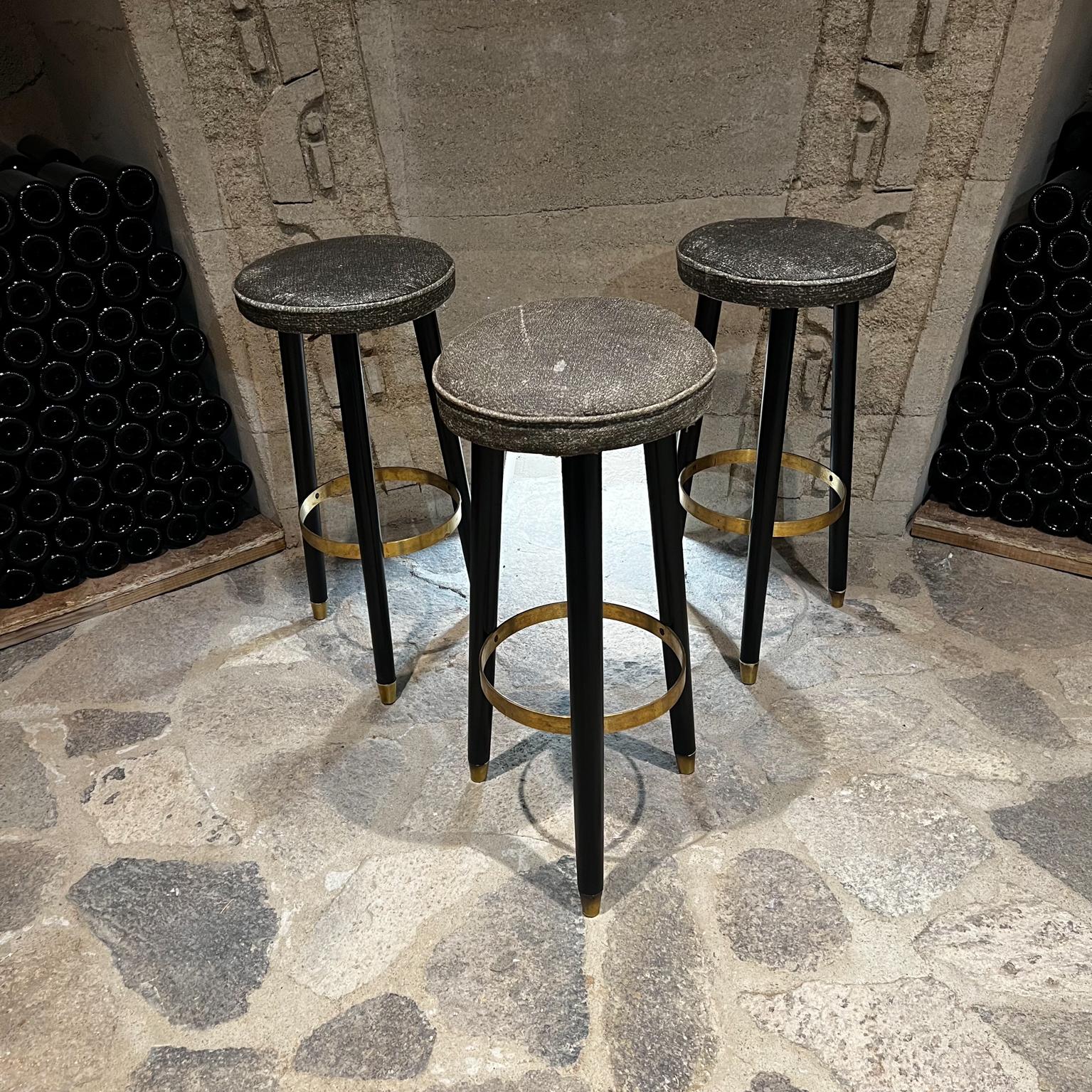 Sensational 1950s Bar Stools Set of 3 Gray Naugahyde, Brass & Black Satin Wood
Made in Mexico.
Solid wood legs with black satin finish
Refreshed preservation to the wood finish.
Brass ring for footrest support provides stability.
Retains all