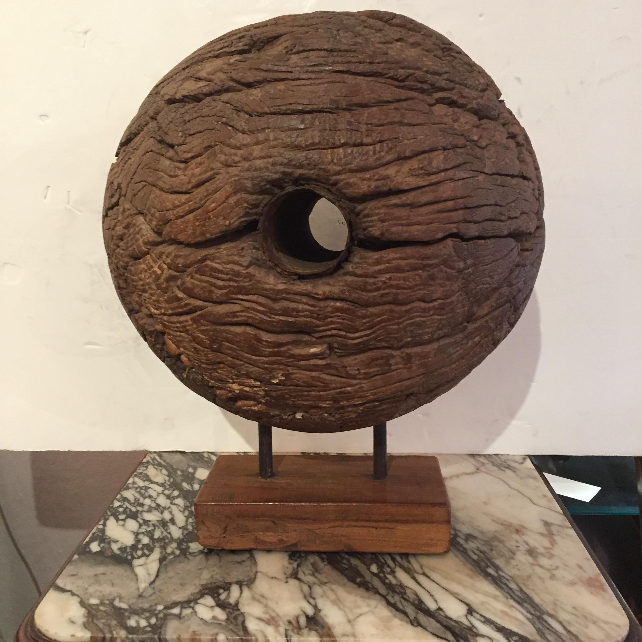 A fabulous mounted found object sculpture that's an impressively bold knotty and worn ship's pulley with simple modern black iron base.