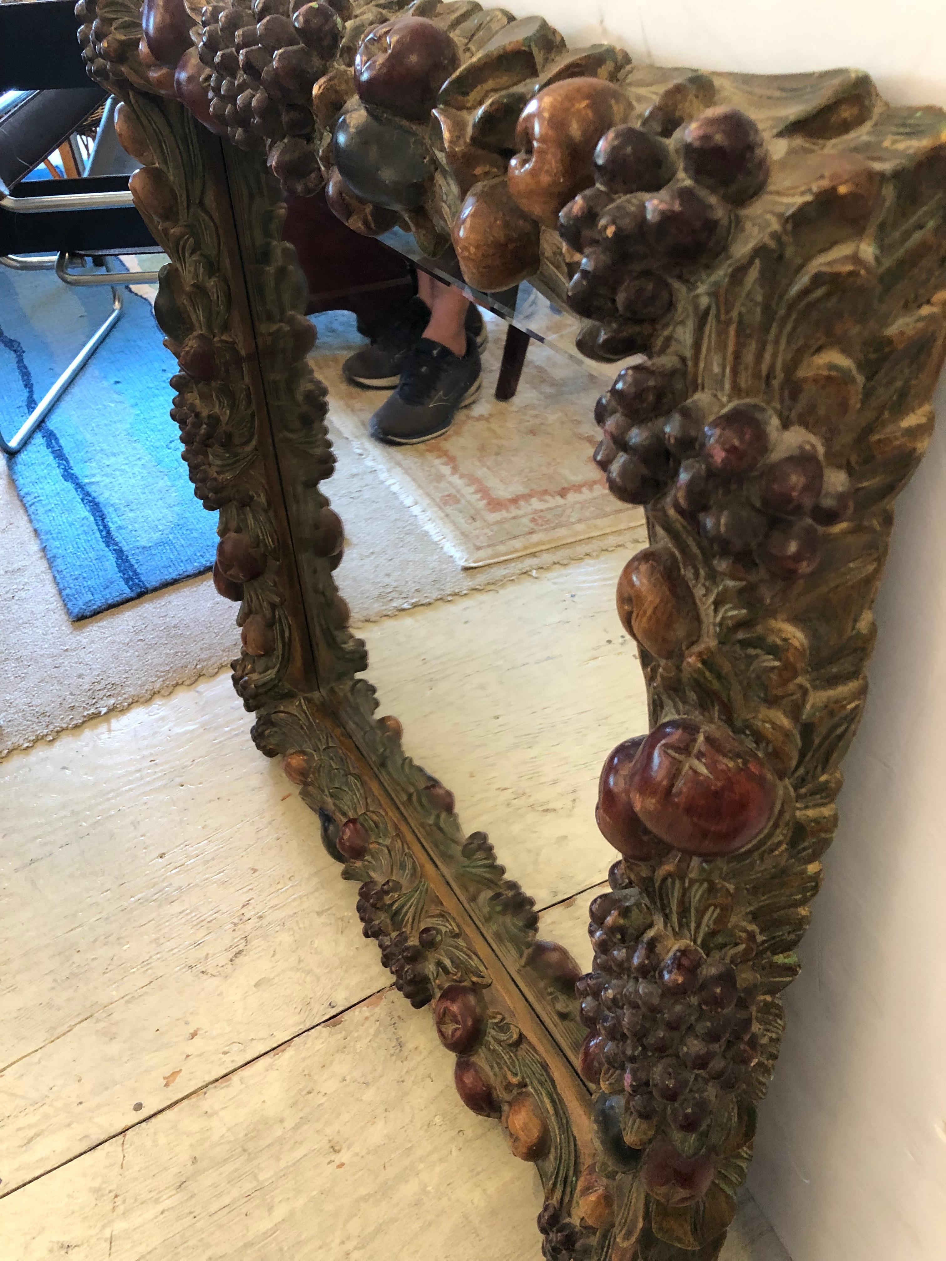 A rare beauty found in a vintage heavily carved square mirror having fantastic chunky frame with autumnal dark subtle colors adorned with fruit and foliage. There is a nod to Black Forest style with its moody woodsy feel. Mirror is 23.5 square and