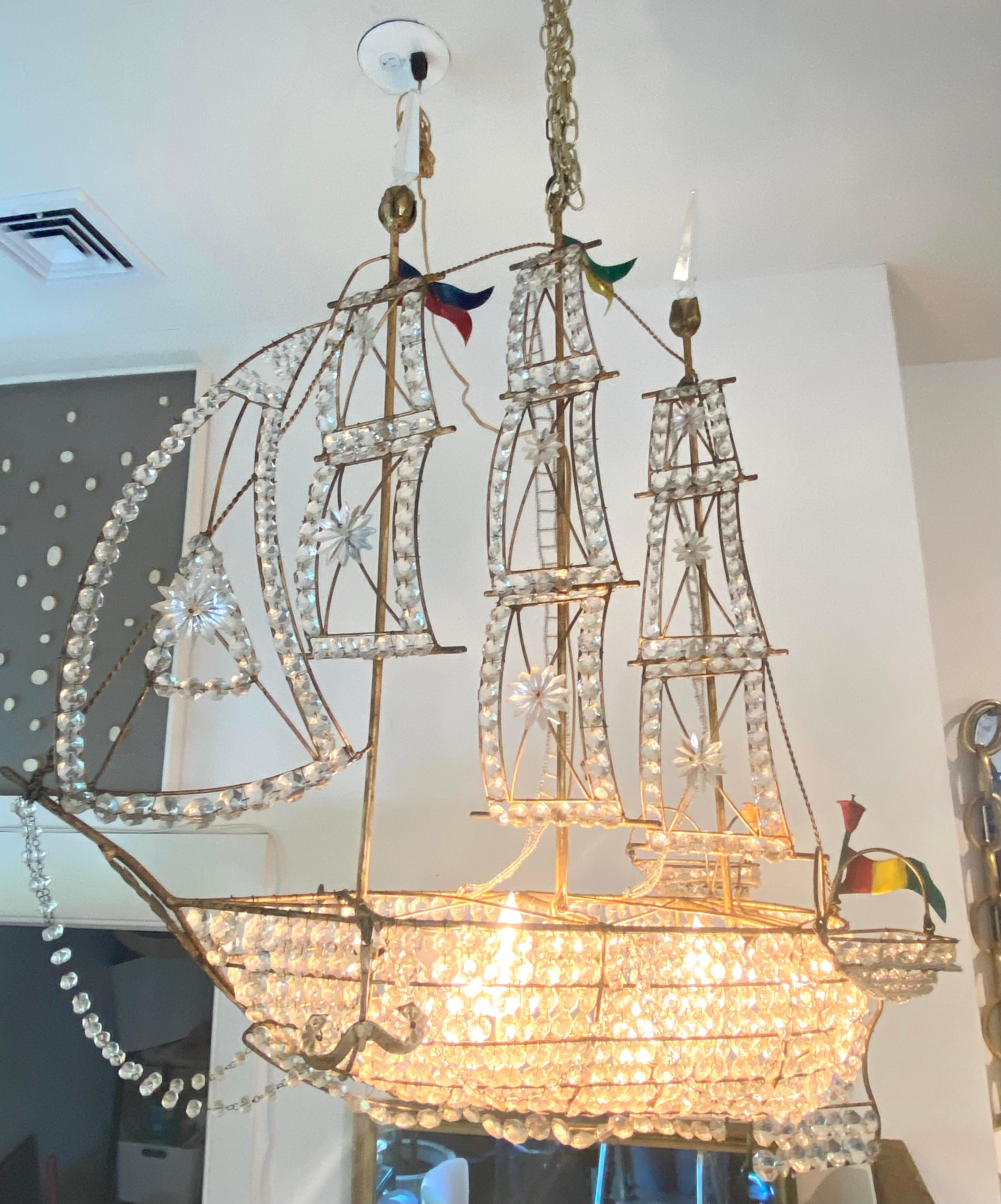 Un navire à trois mâts avec un cadre en métal doré, des prismes en cristal et des drapeaux de tole.... une pièce très spéciale et unique.... 