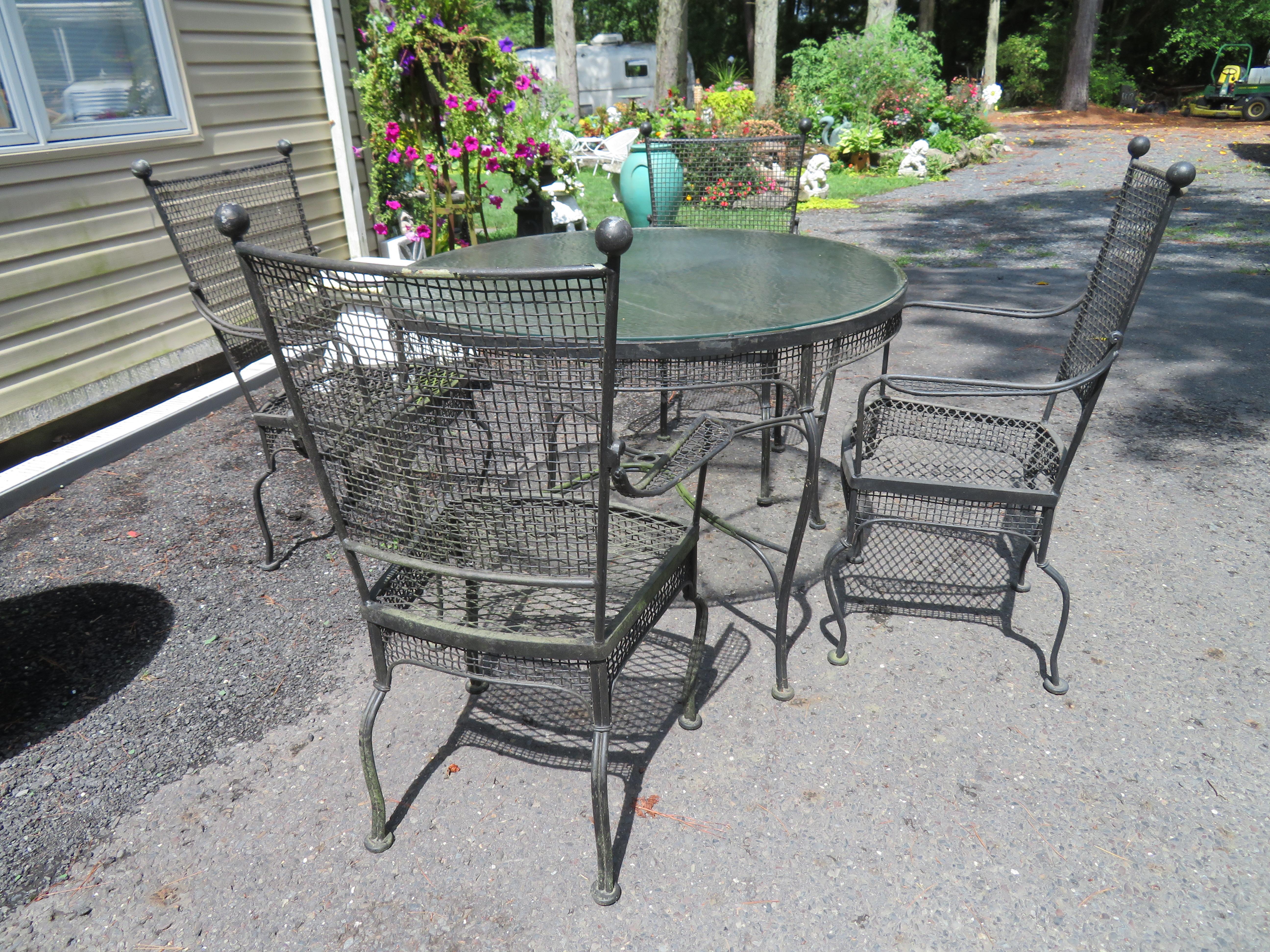 Very rare Russell Woodard 1960’s 5 piece outdoor patio dining set. The heavy mid-century modern armchairs each have 2 large Iron ball top finials on top along with thick iron mesh construction throughout. The matching table has a thick mesh apron