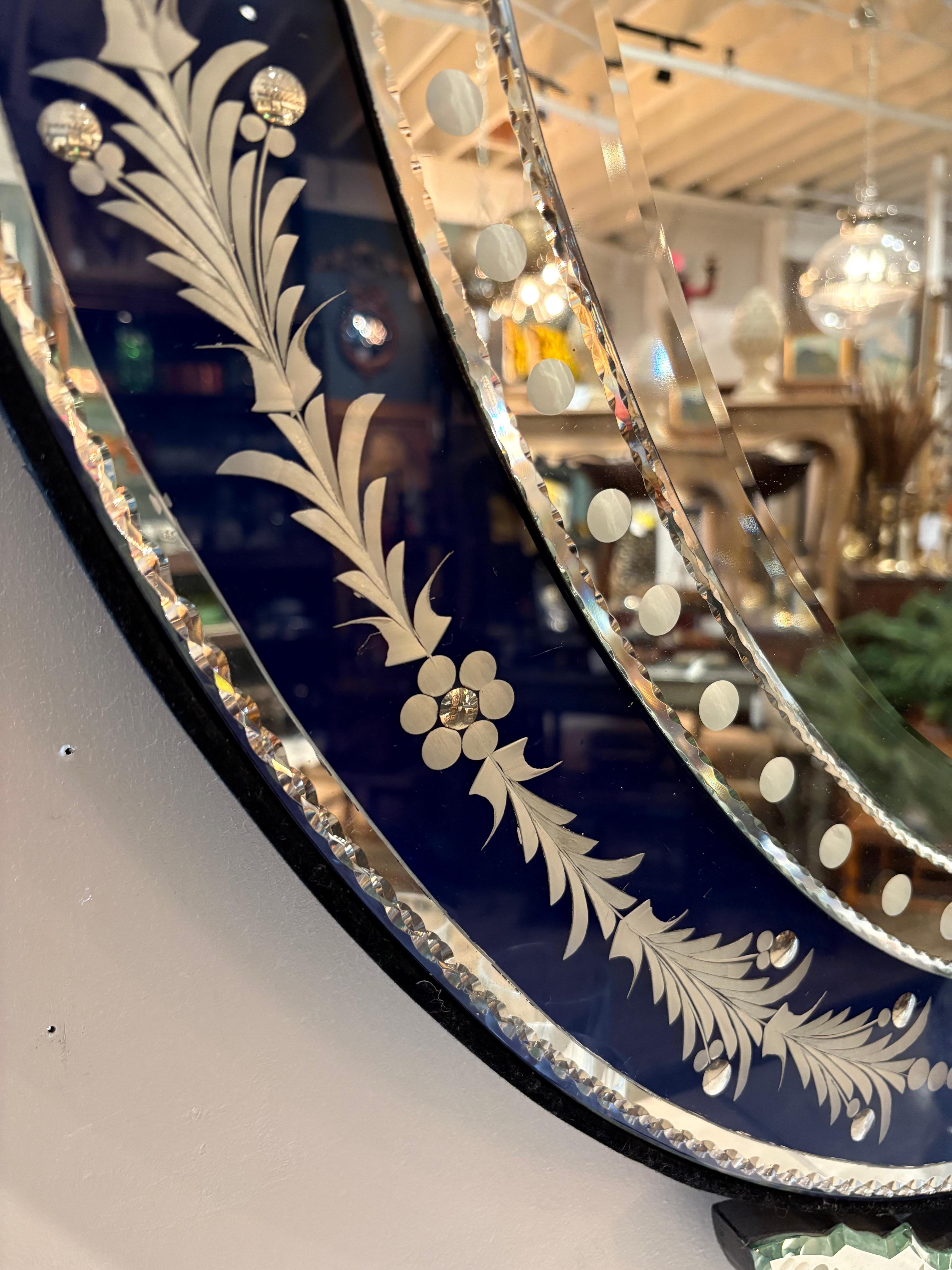 Superbe miroir vénitien ovale orné d'un verre bleu foncé sur le pourtour.  et de magnifiques détails.  Les bords latéraux sont doublés de velours.