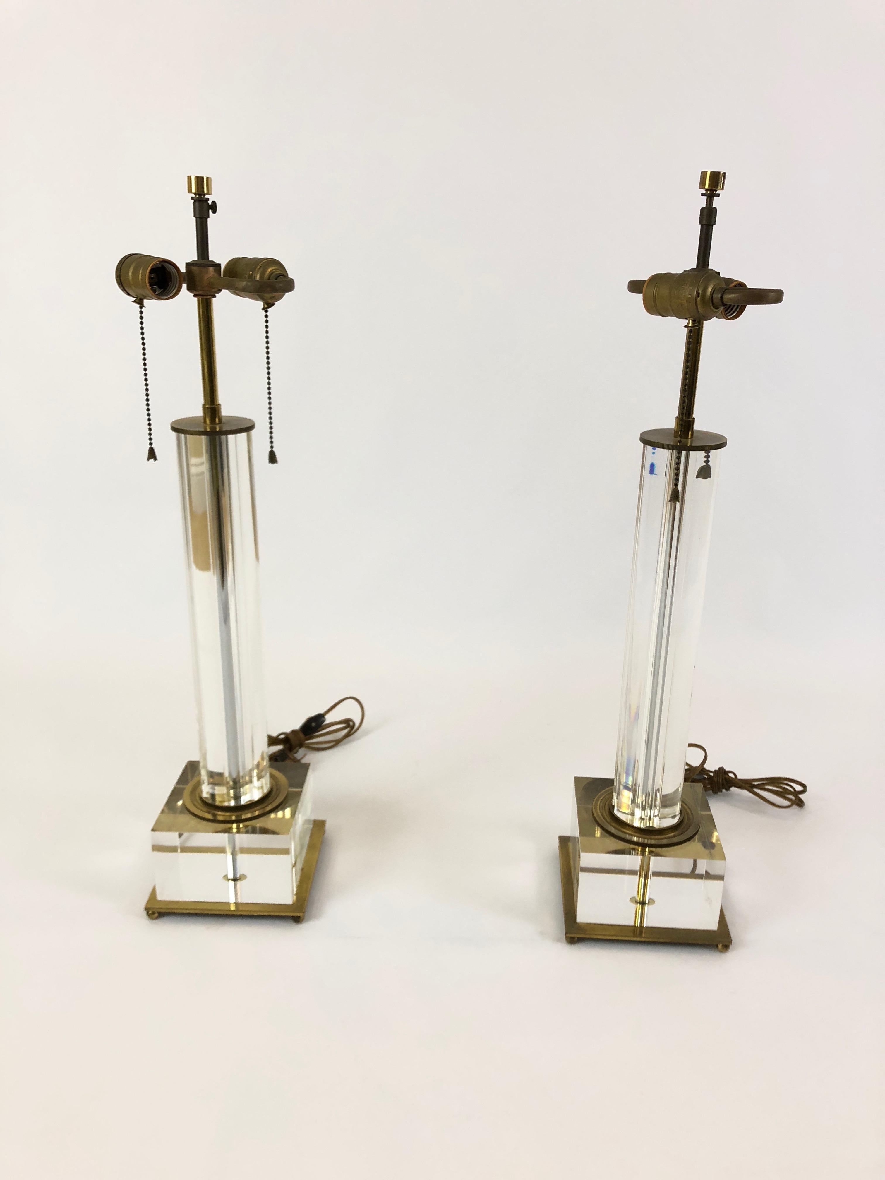 Elegant and glamorous pair of Lucite and brass Mid-Century Modern lamps having chunky 6 x 6 inch square bases and glistening columns with original string shades. There are double sockets in each lamp.