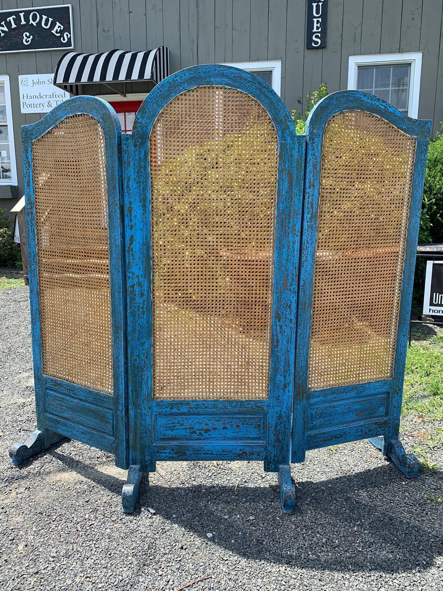 A stunning 3 panel screen having turquoise Caribbean blue painted scrubbed wood frame and feet with natural colored caning on the panels.
71” H middle panel
68” H side panels.
 