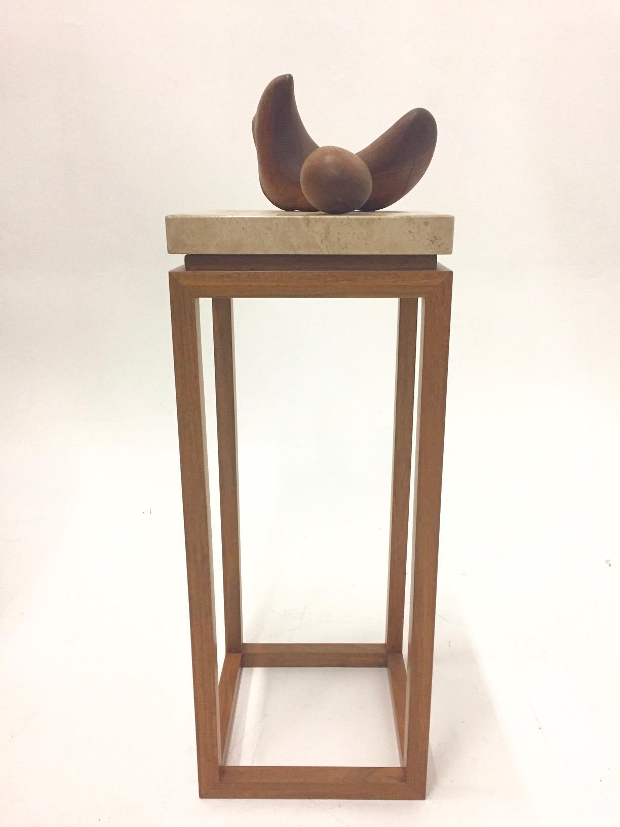 A sophisticated freestanding sculpture signed by the renowned artist Arthur Williams, having two smooth walnut shapes placed on a lovely slab of travertine, floating on a superb walnut pedestal with clean lines.