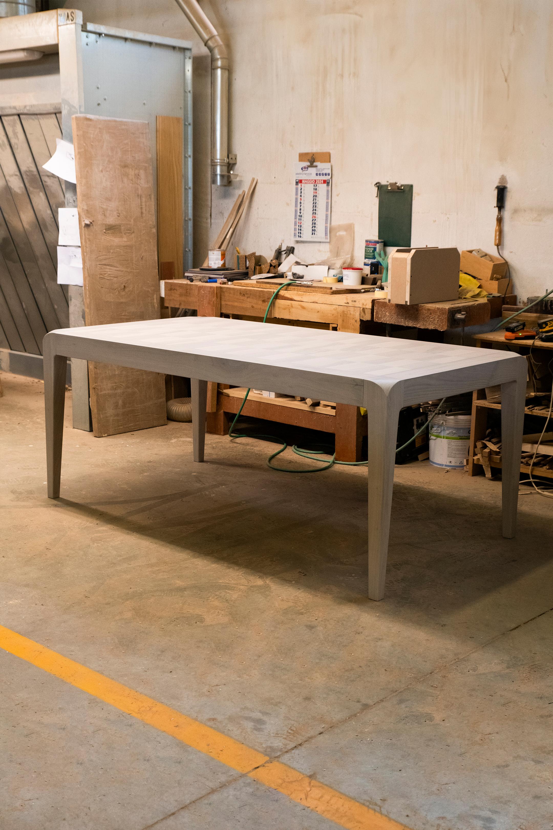 La table extensible Sentiero en bois massif est l'expression du design contemporain et de l'artisanat italien de haute qualité. De forme rectangulaire, il présente une structure et des pieds en gris précieux ou en noyer naturel avec incrustation et