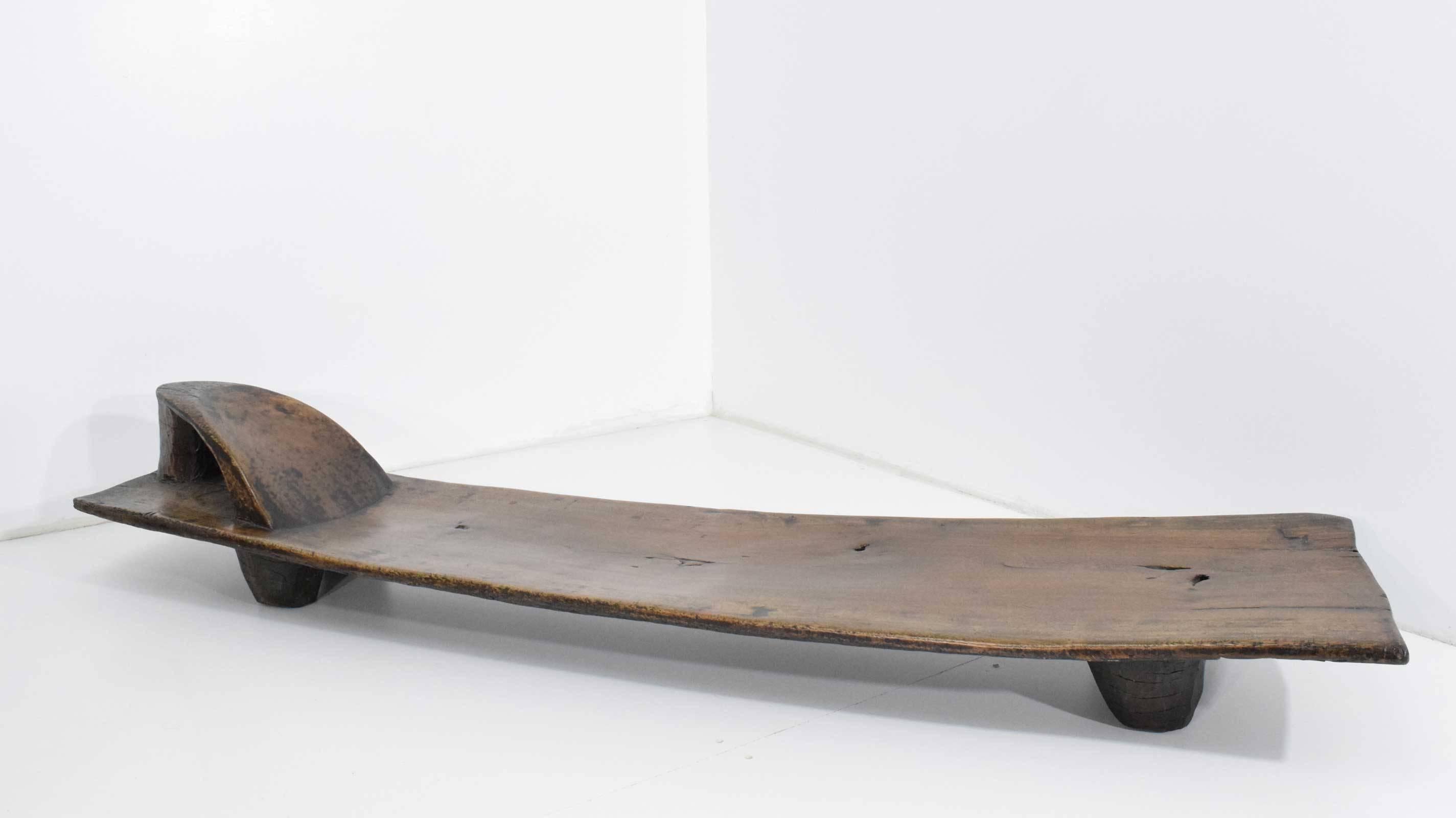 Bench is a solid piece of very nicely patinated wood. Low height, an open area behind the pillow, the pillow being integral and carved. Provenance: from the collection of Maria Manetti Shrem and Jan Shrem, obtained through Christies Auction house.