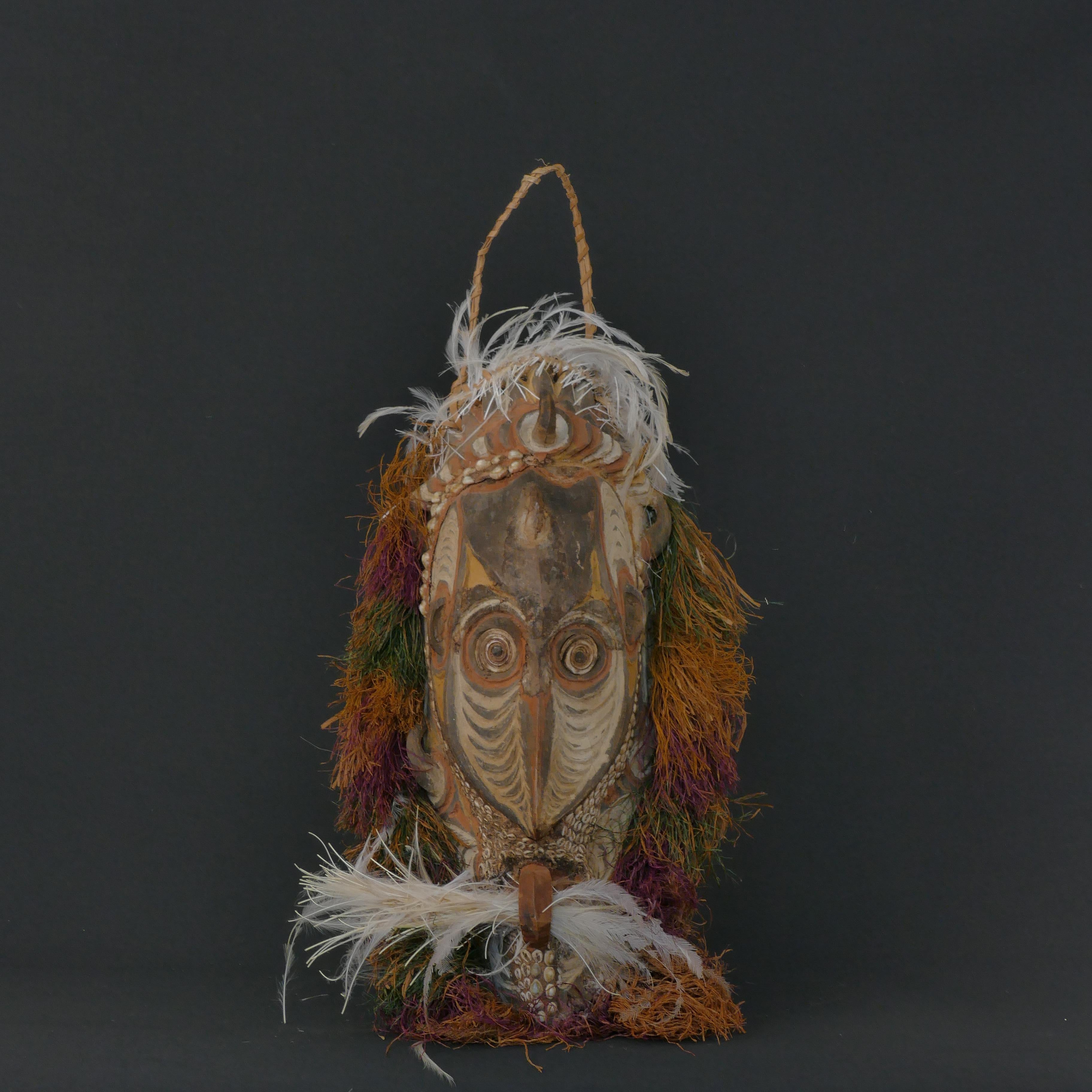 Beautiful and unique ceremonial mask from the Sepik River area of Papua New Guinea made of wood, cowrie shells, feathers, clay, pigment and grass.  

Small parts are missing on the upper forehead. 

Measures:
Height 53 cm 
Width 25 cm 