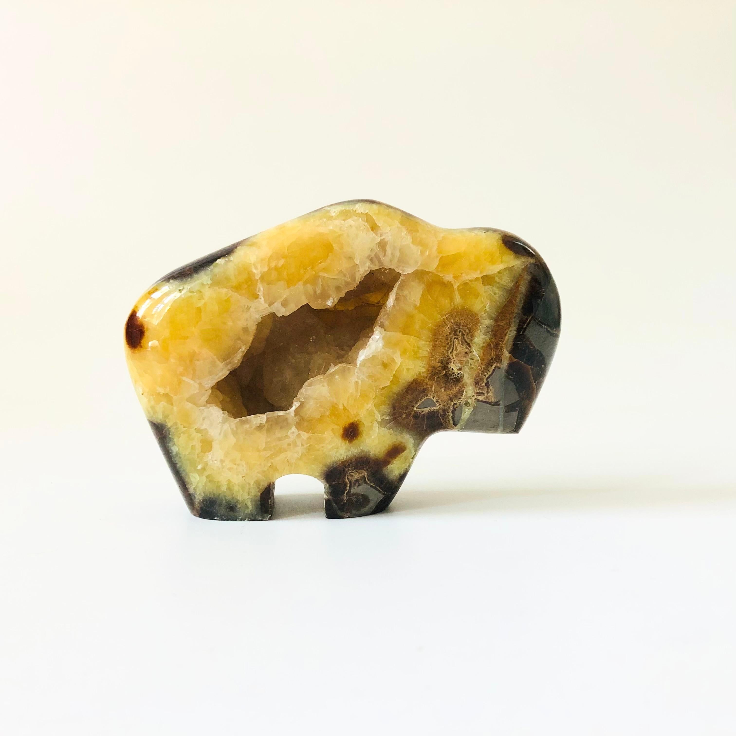 A vintage buffalo made out of carved and polished septarian nodule stone. Beautiful natural tri color pattern to the stone in yellow, brown, and gray. Nice simple form. Features a hollow portion of the stone on one side.

