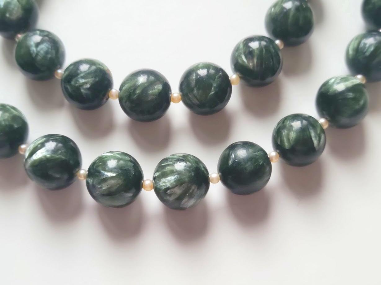 Die Kette ist 27 Zoll (68,5 cm) lang. Die glatten runden Perlen haben eine Größe von 13.5 mm. 
Die Perlen sind tief waldgrün mit silbrigen, federartigen Glimmerbeimischungen. Authentische, natürliche Farbe. Es wurden keine thermischen oder anderen
